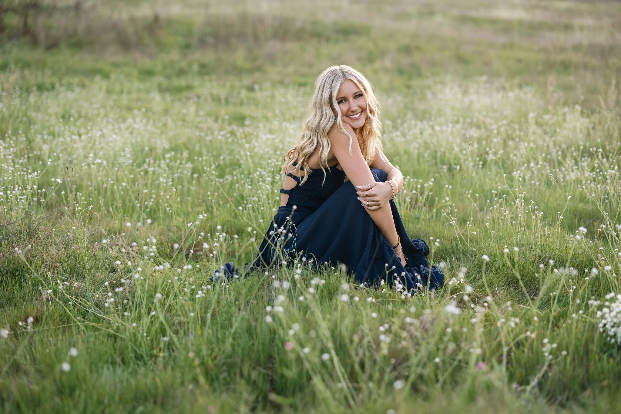 Folsom high school graduating senior wearing a long flowy blue dress in a field of flowers