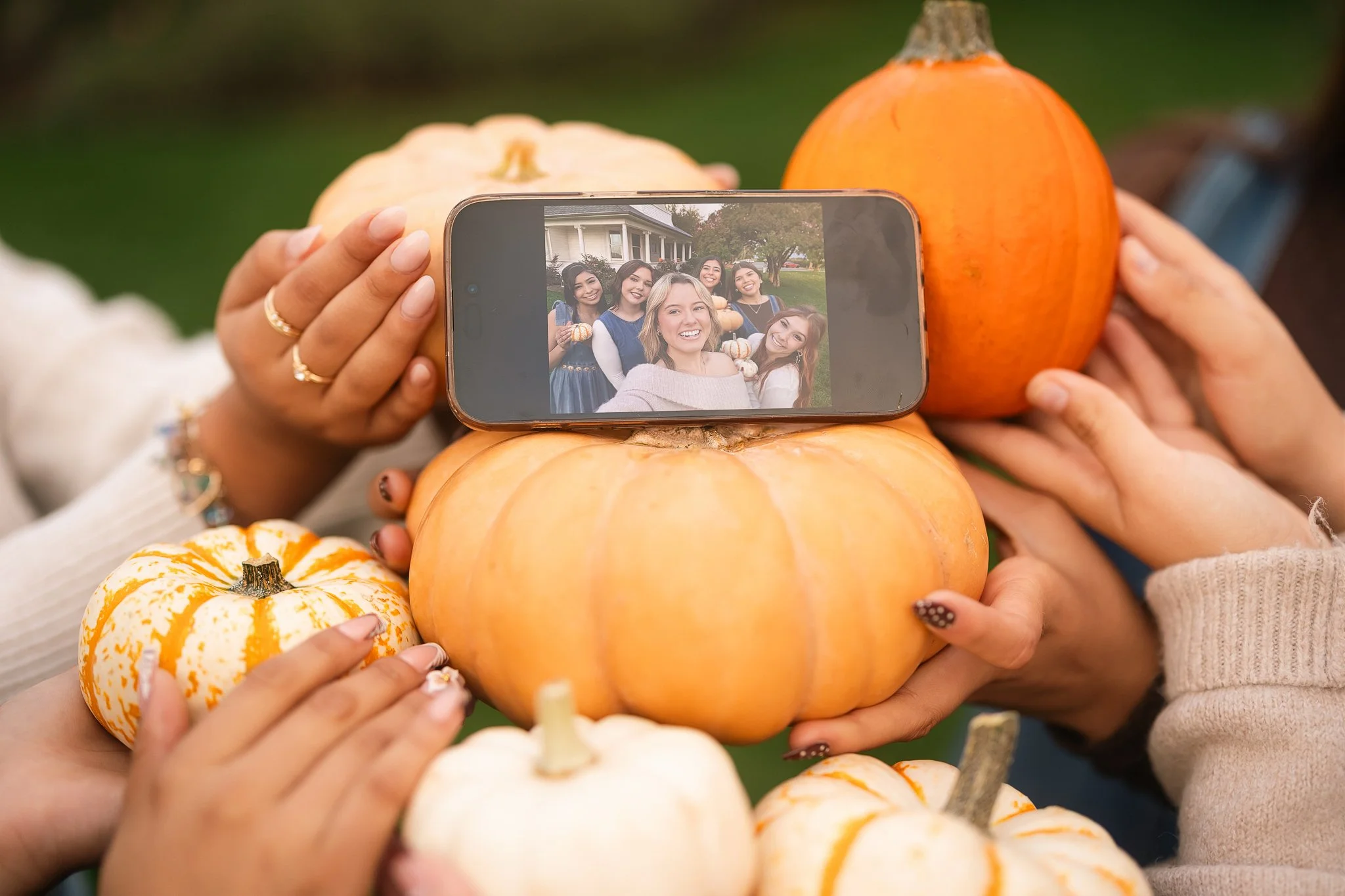 MC Senior VIP Team members holding pumpkins around a phone showing a group selfie during a fun fall senior team photoshoot in Northern California.