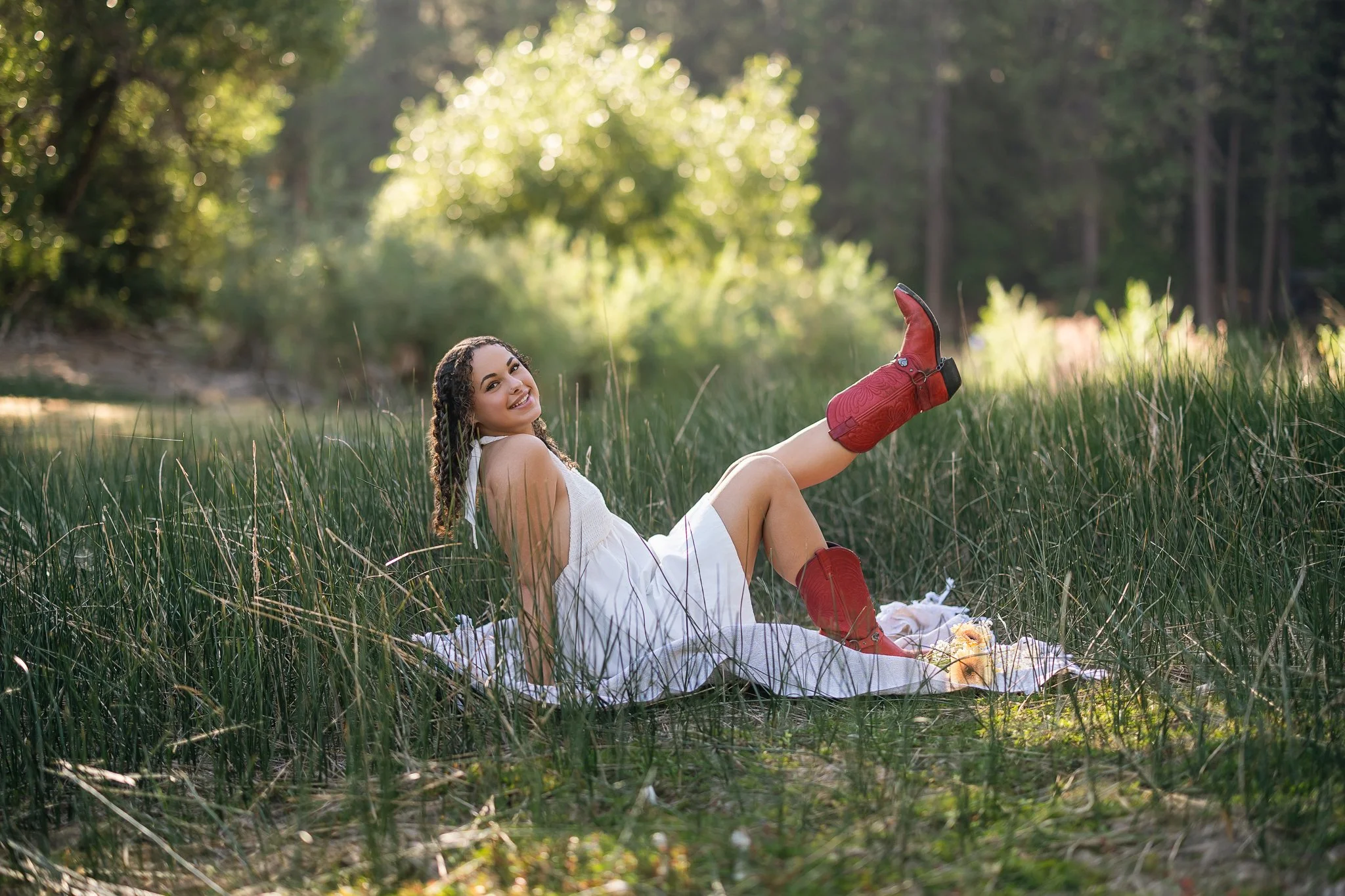Vista del Lago High School senior in a white dress and red cowboy boots during her fall senior pictures at Sly Park near Pollock Pines, California.