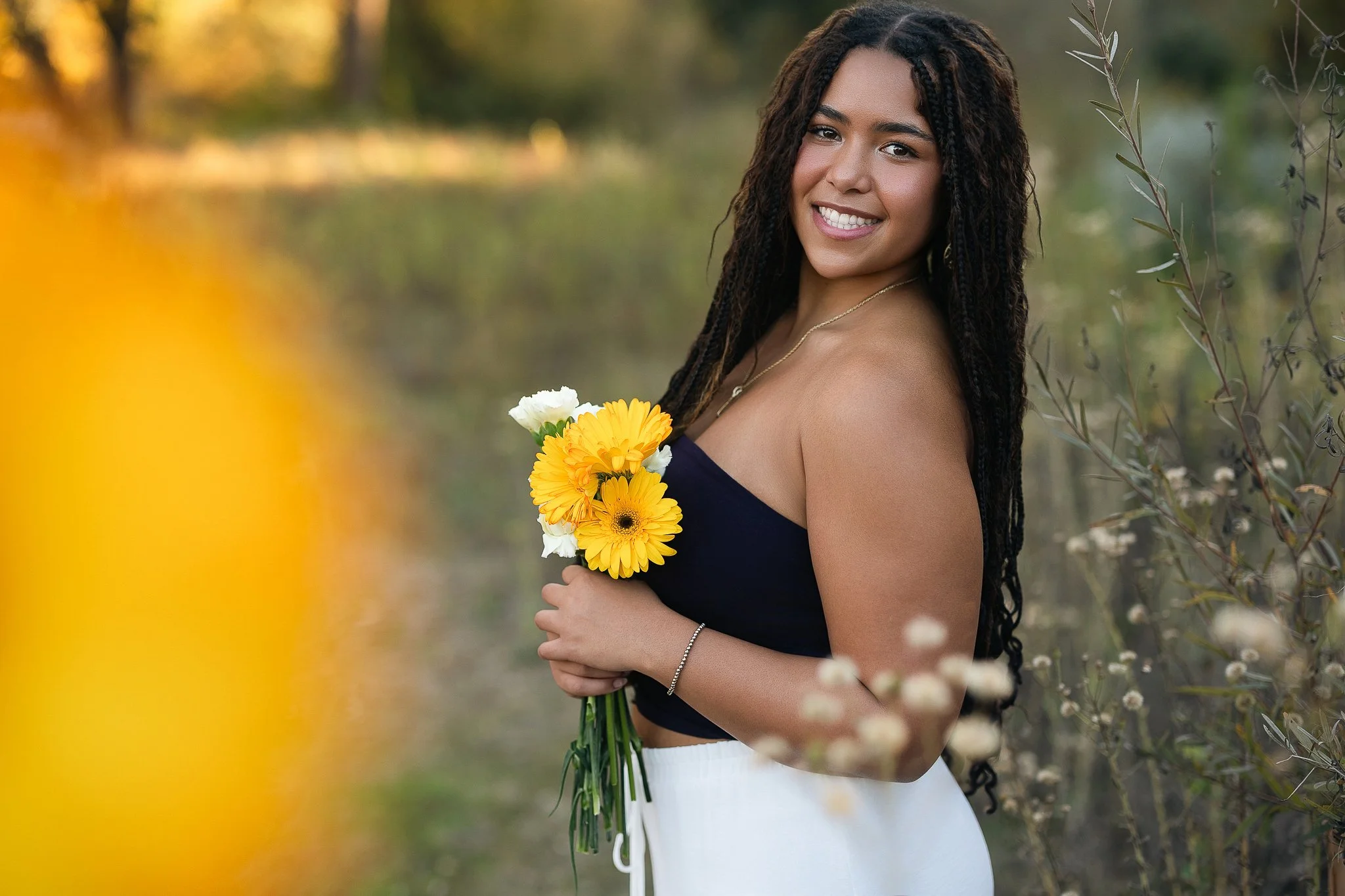 Oak Ridge High School senior holding a bouquet of yellow gerbera daisies at golden hour, Folsom Lake senior session at Browns Ravine.