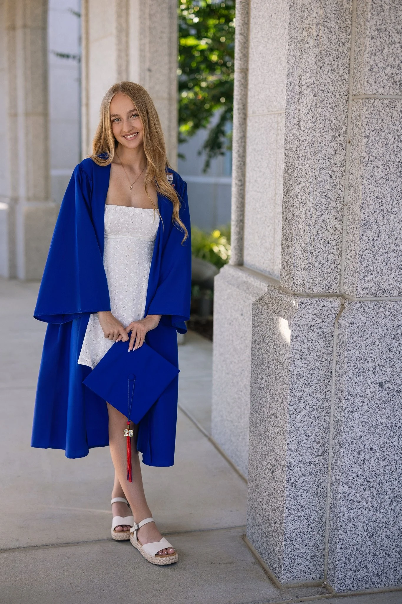 Folsom High School graduating senior wearing her blue cap and gown for grad pictures in Folsom, California.