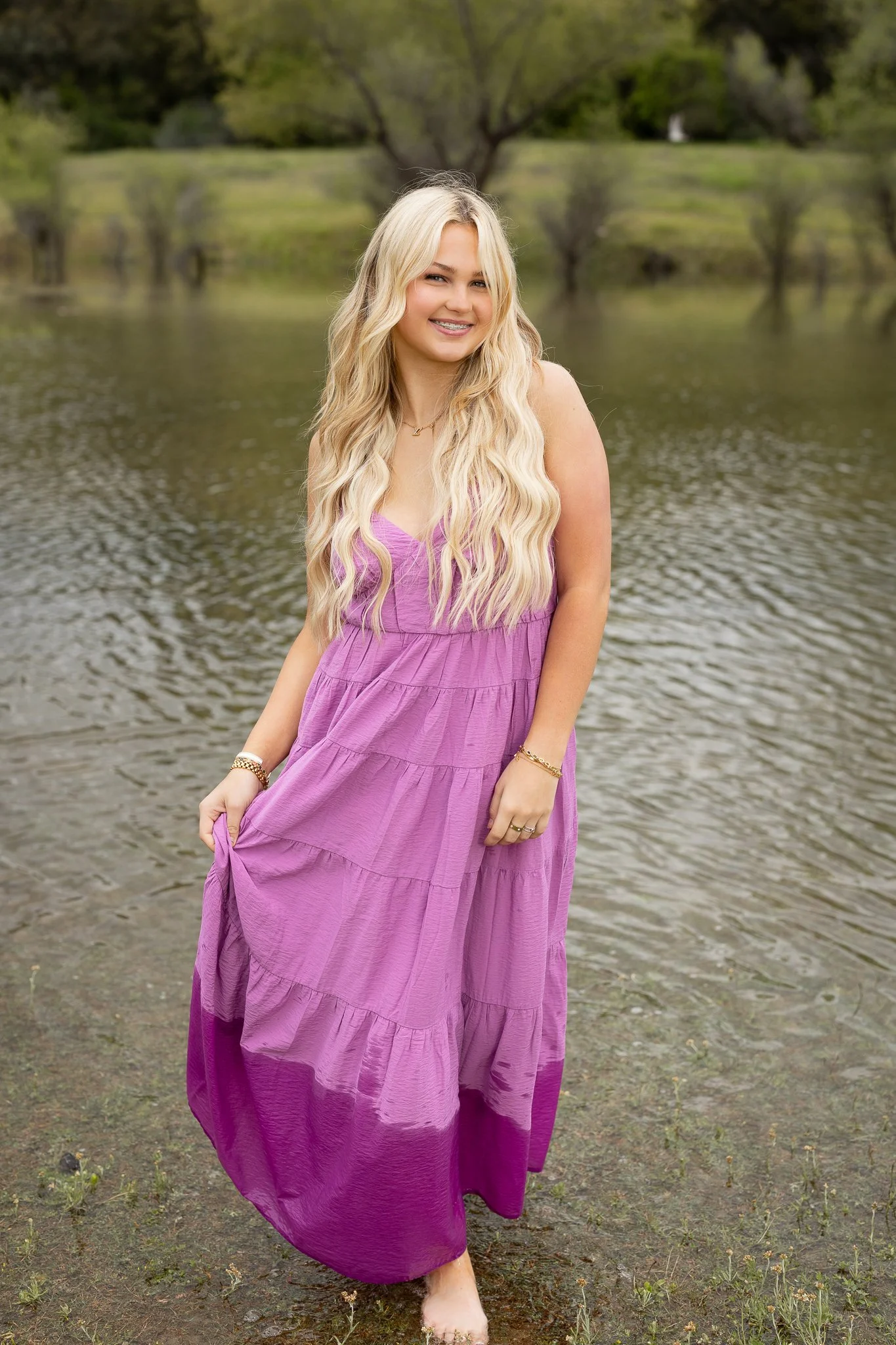 Roseville High School senior girl wearing a pink maxi dress for her senior pictures by the water at Folsom Lake in Northern California.