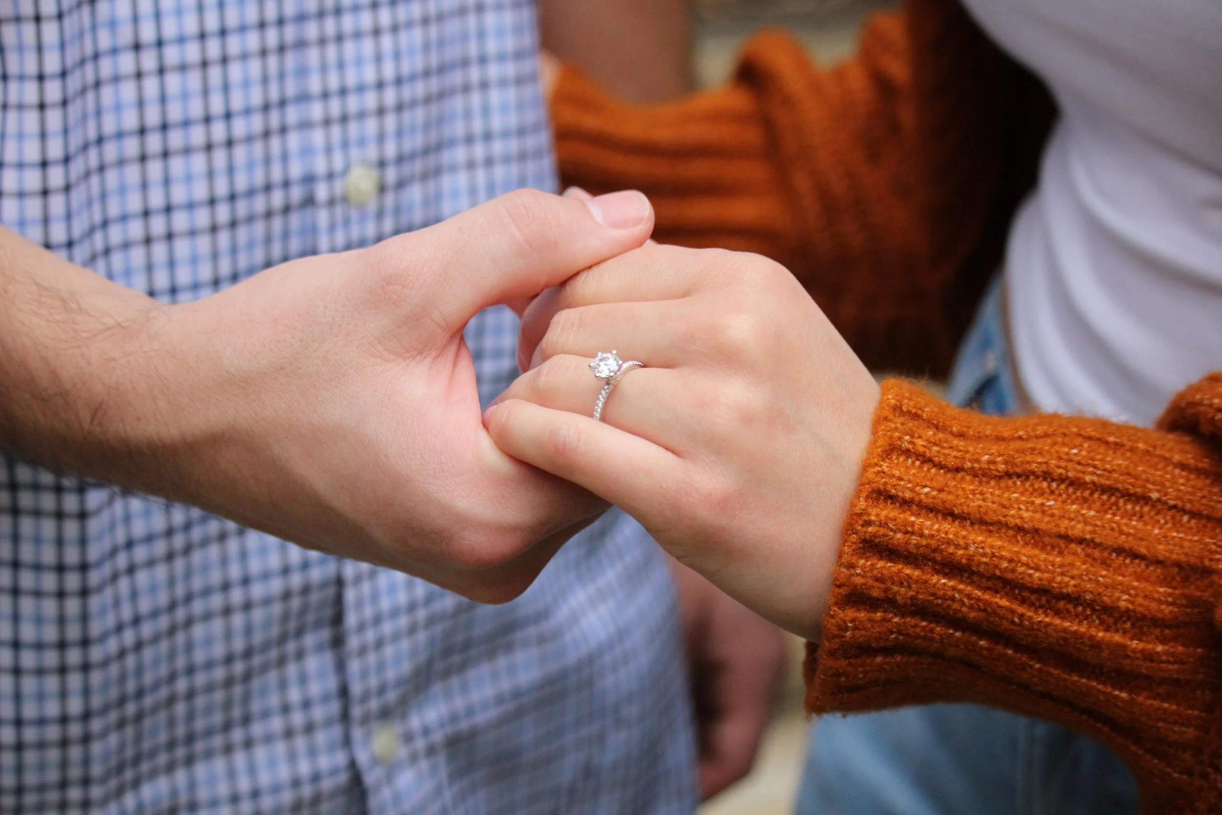 couple holding hands with engagement ring