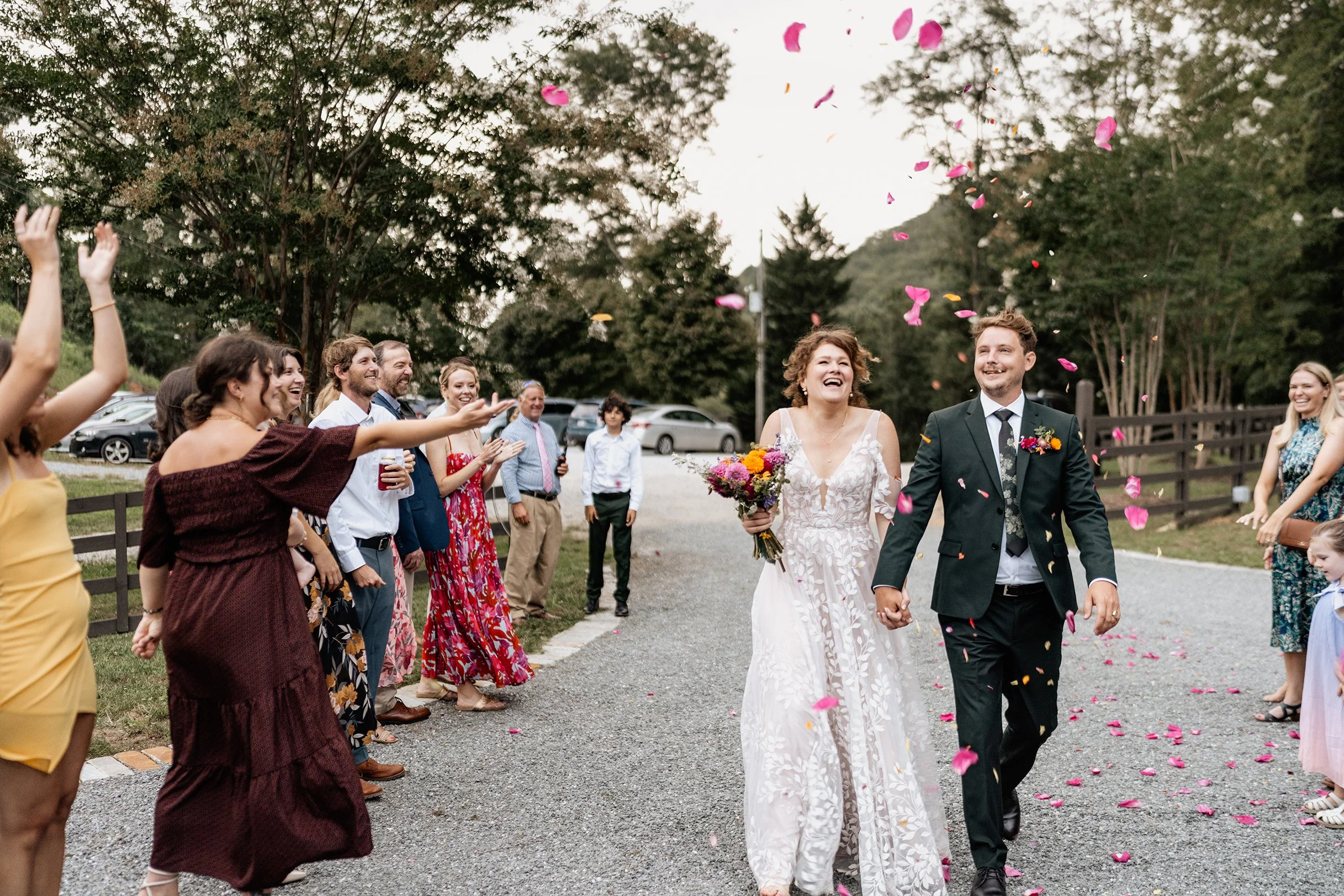 Greyson and Miranda walking through a joyful petal toss at their Appalachian mountain wedding exit