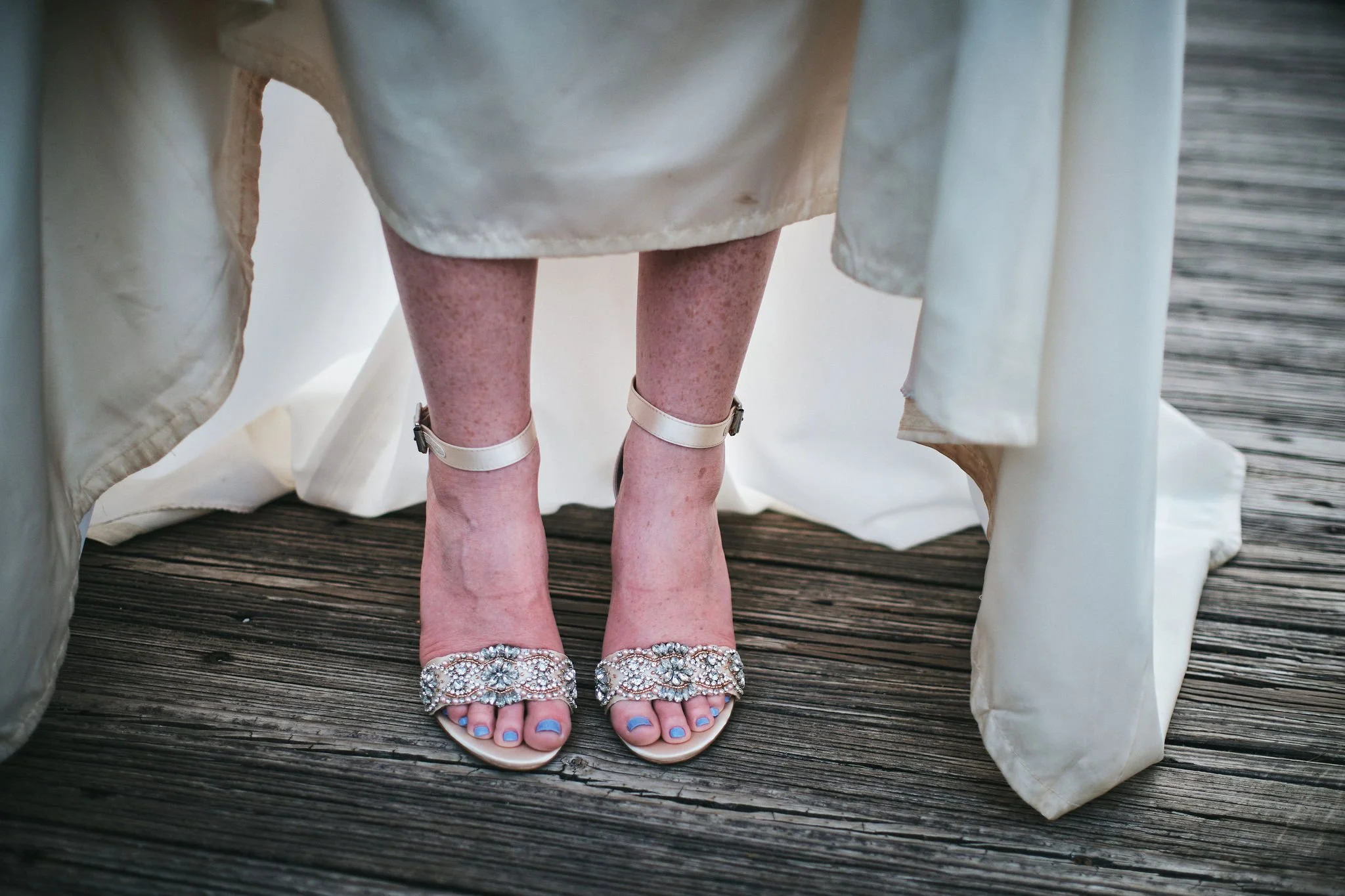 Close-up of Margo's delicate sandals on rustic wooden bridge planks during her Blue Ridge Georgia elopement, intimate wedding detail photography by Appalachian Wedding Photography