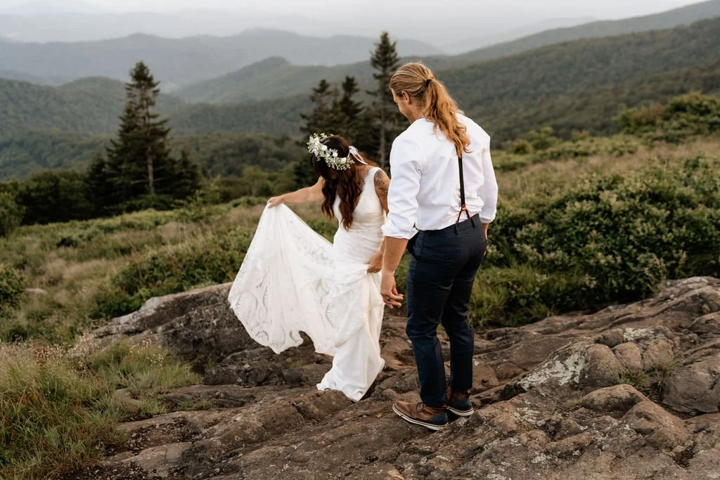 Groom helping bride over rocky trail in her hiking boots.jpg