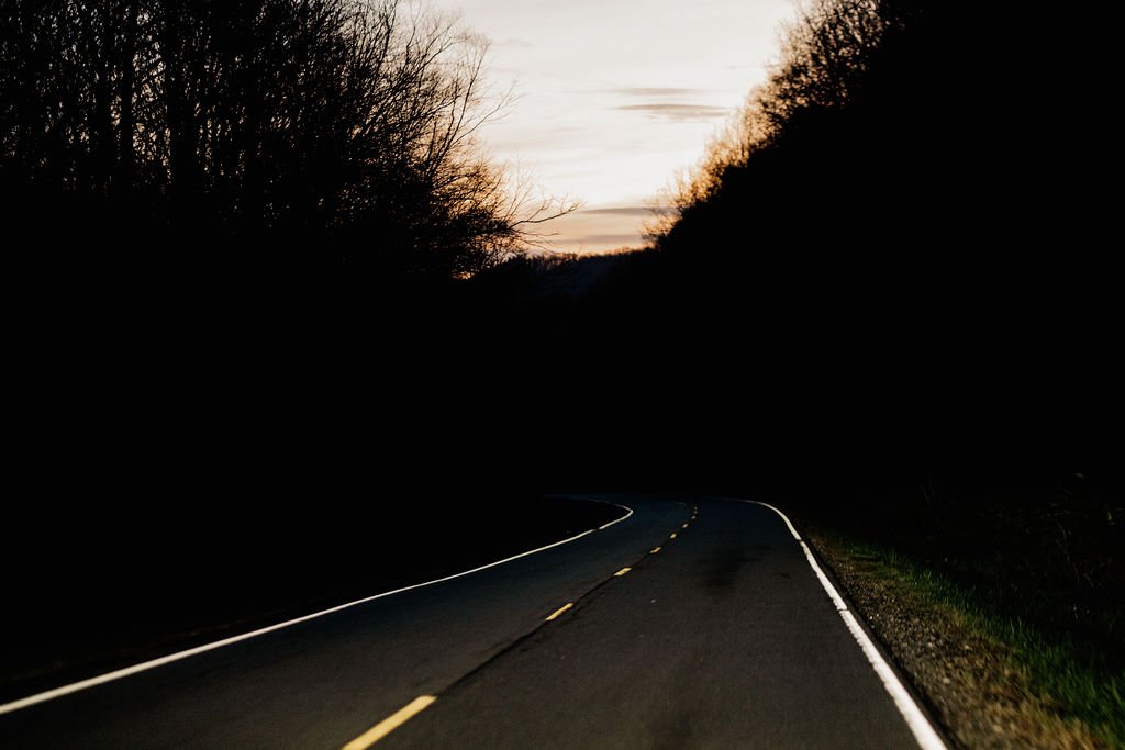 Winding mountain road to Wayah Bald at sunrise, silhouetted tree line against the early morning sky in Nantahala National Forest, NC