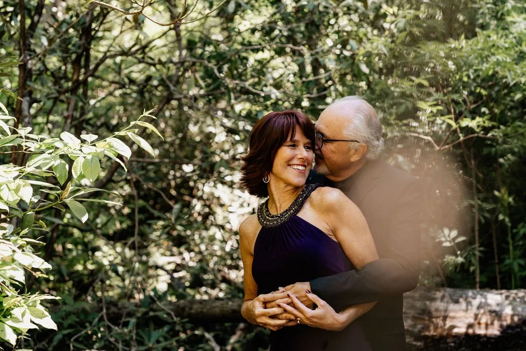 Couple smiling and embracing surrounded by lush forest greenery at their Helton Creek elopement in Blue Ridge, Georgia, May 2026