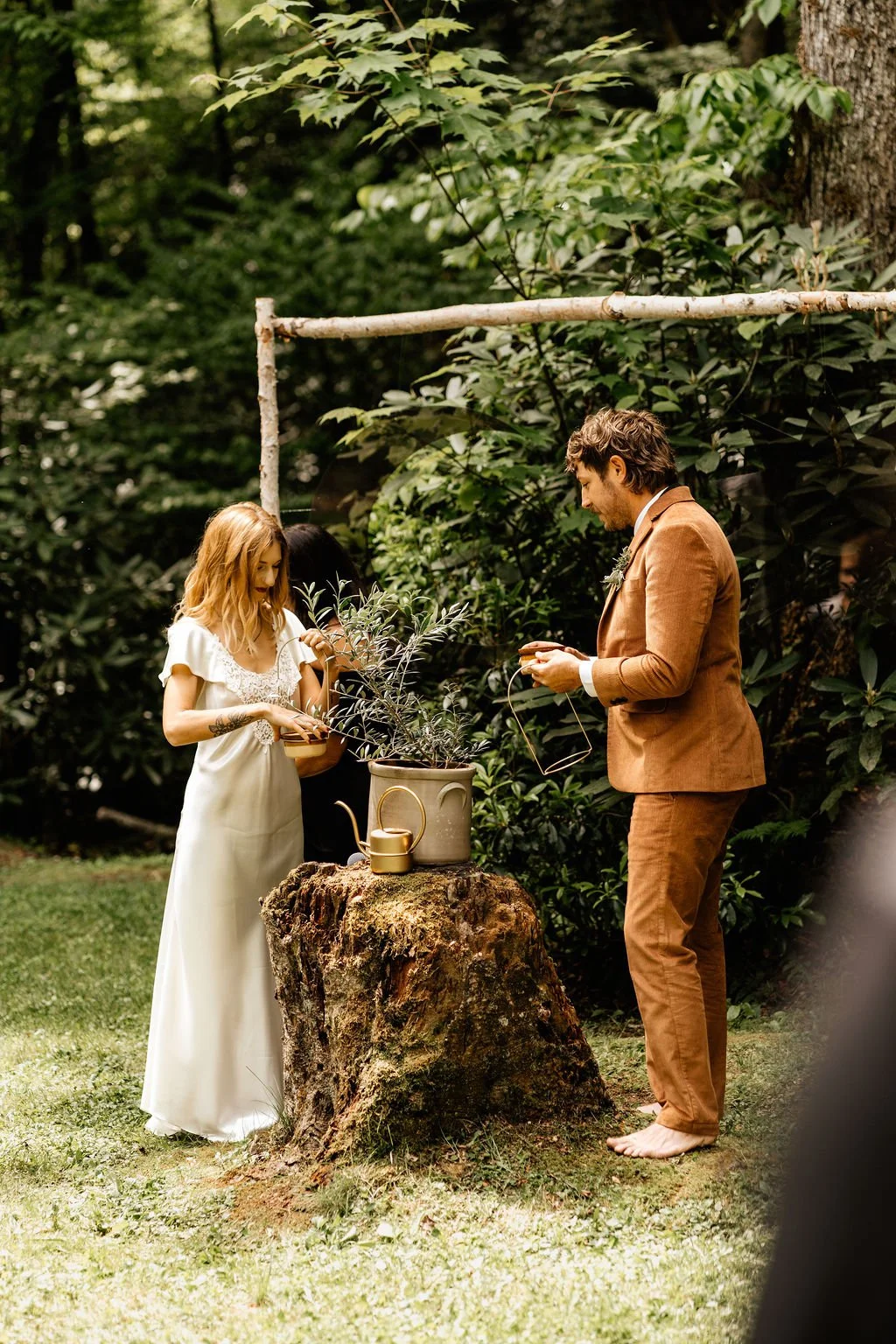 Hope and Chase standing at a rustic branch altar during their forest ceremony at Huffman Creek in Robbinsville, North Carolina