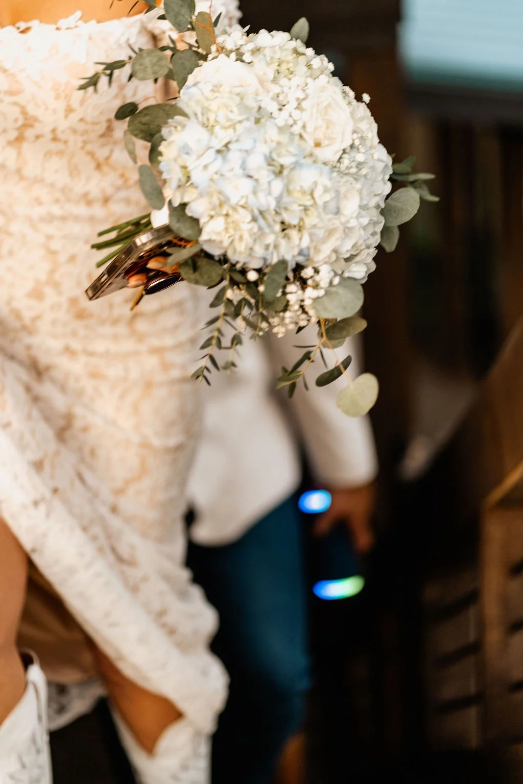 Erin's lace-sleeved arm holding her blue hydrangea and white rose bouquet at her side as she walks through the cabin doorway during their Blue Ridge Georgia elopement