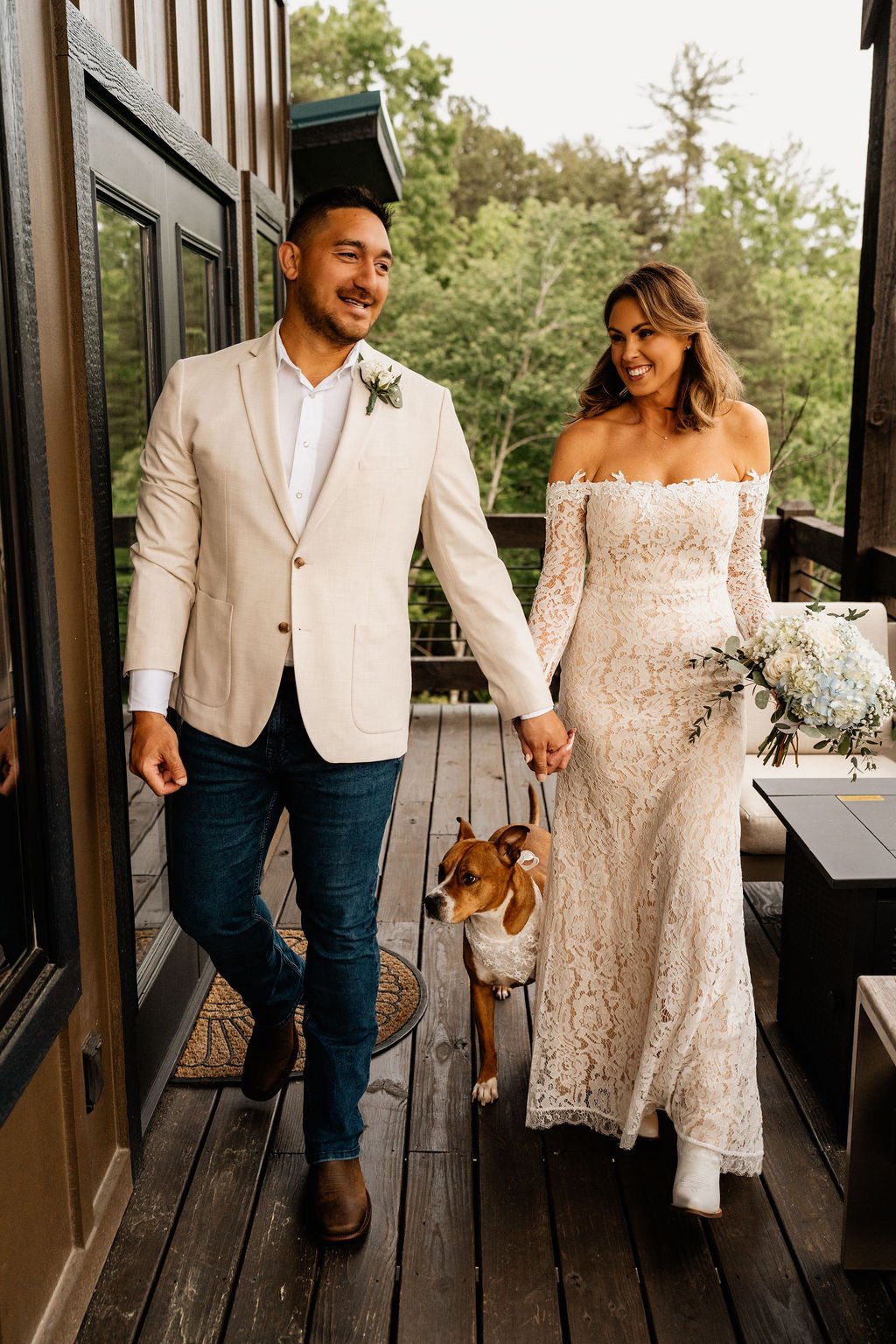 Erin and William walking hand in hand on the cabin deck with their dog between them, both smiling after their ceremony during their Blue Ridge Georgia elopement