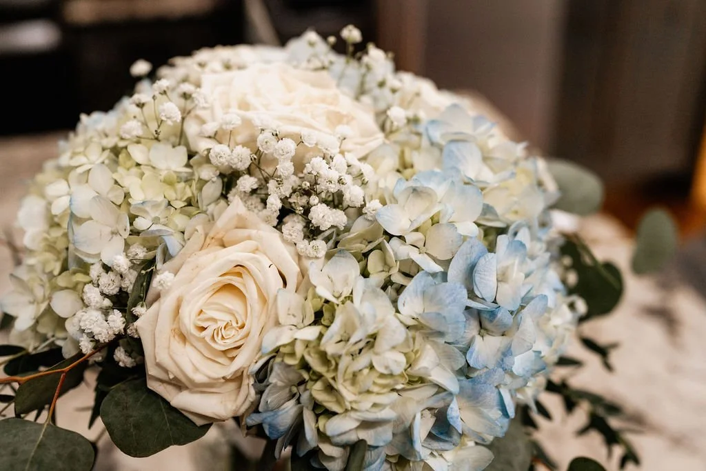 Close-up of Erin's bridal bouquet with white roses, blue hydrangeas, baby's breath, and eucalyptus during her Blue Ridge Georgia cabin elopement