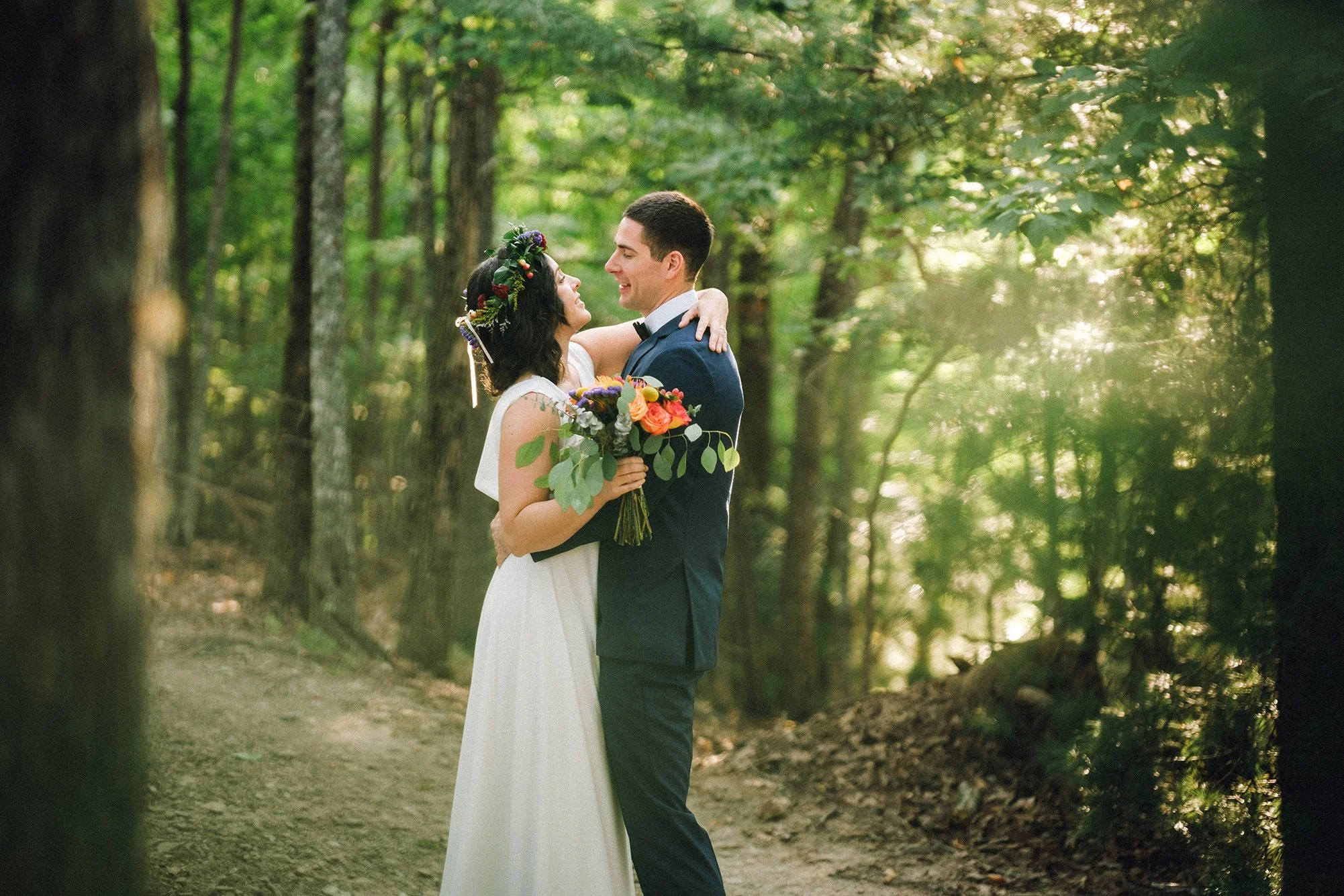 Bride and groom walking through sun-dappled forest during their Blue Ridge Appalachian elopement