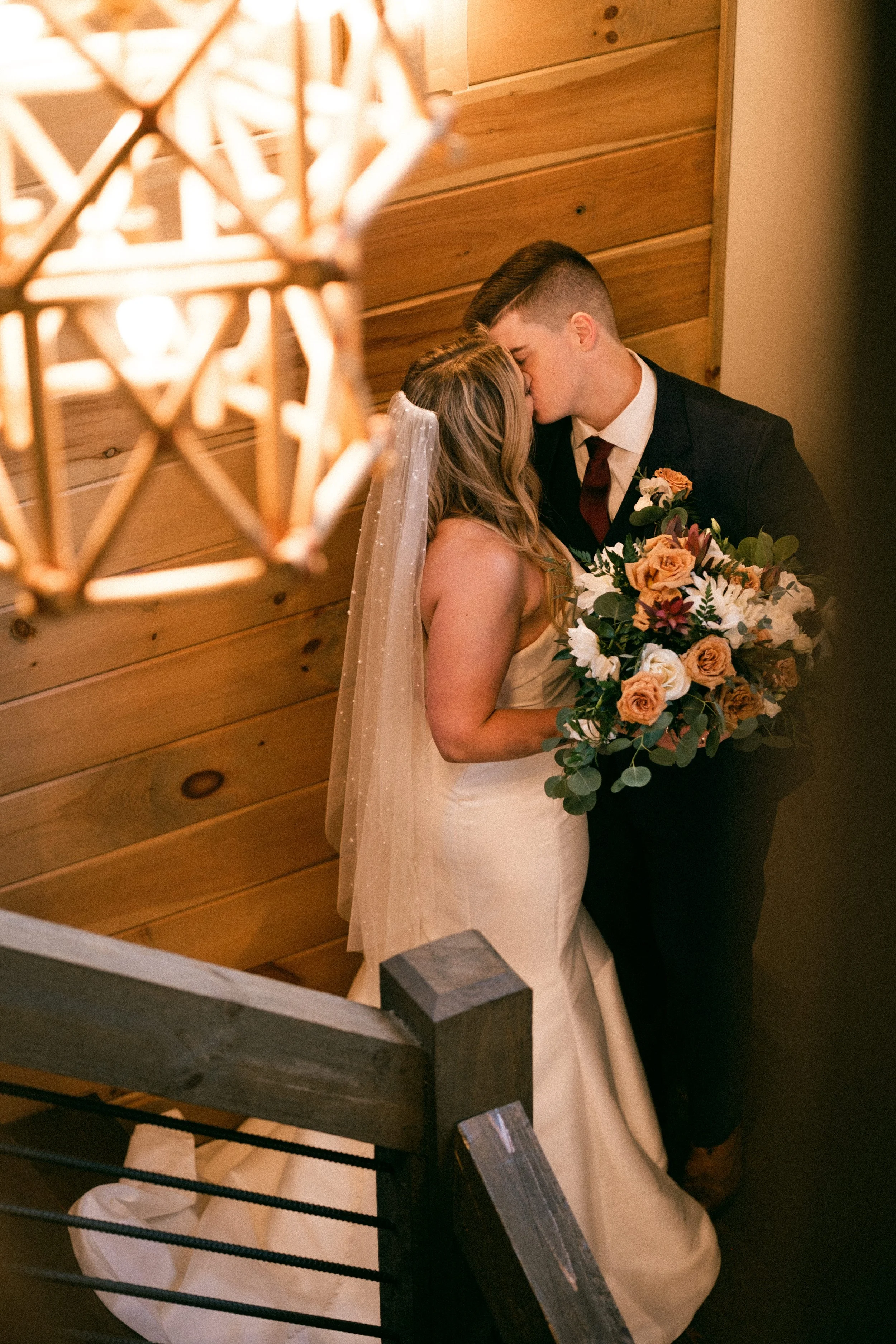 Couple sharing a kiss on a rustic cabin staircase in warm light at their Appalachian mountain wedding
