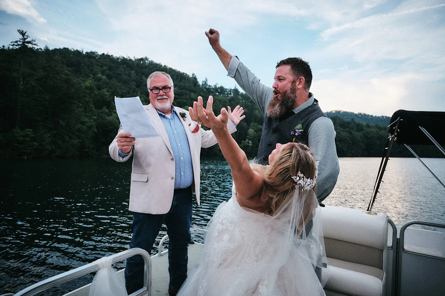 Couple celebrating on a pontoon boat on a mountain lake during their Blue Ridge, Georgia wedding