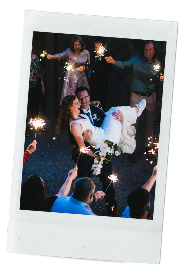 Groom carrying the bride while celebrating their wedding with lucis fire crackers around them