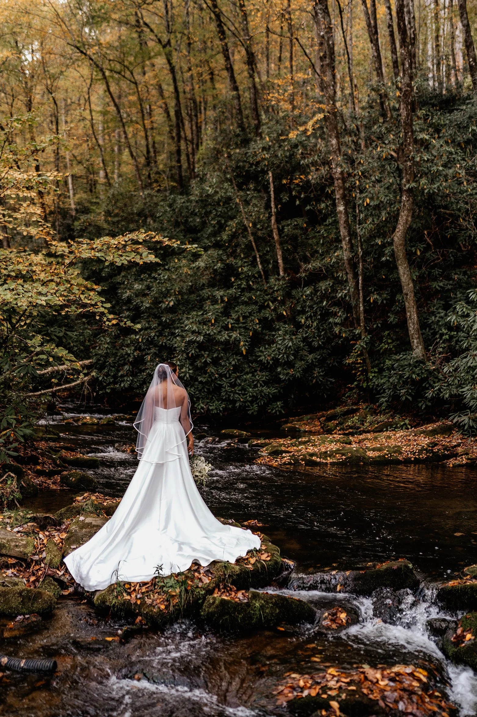 Bride standing in a creek surrounded by autumn forest during a Nantahala, NC elopement