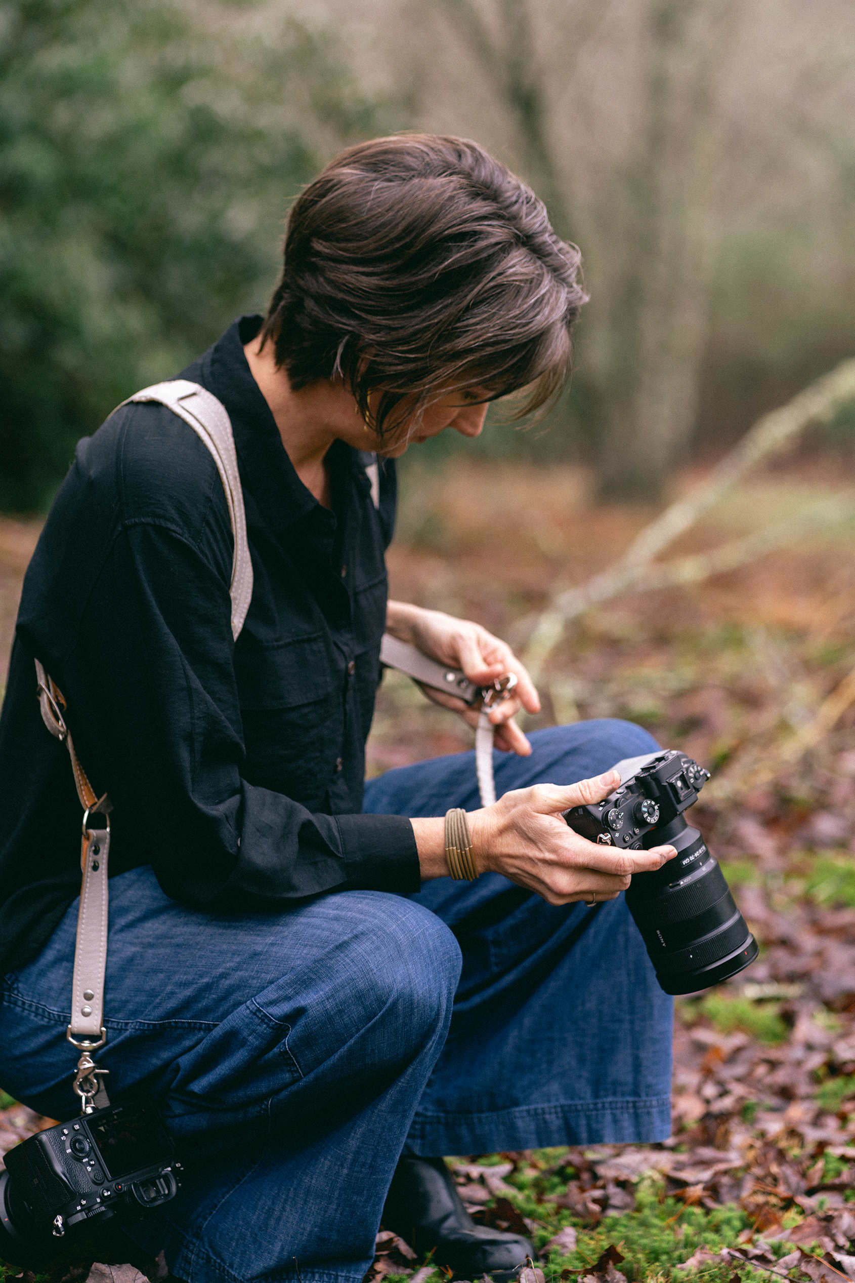 Emilie Gates Sitting in a Squat Position Holding Camera.png
