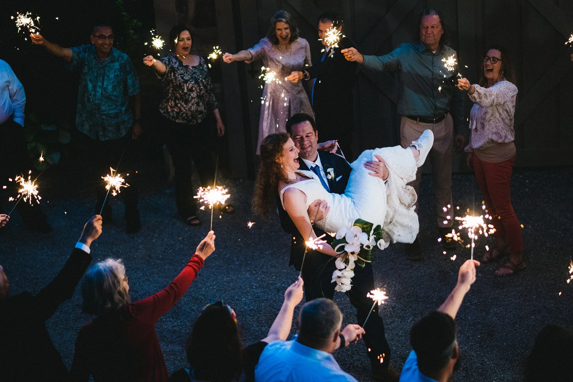 Groom carrying his bride through a sparkler exit at night during their Appalachian wedding