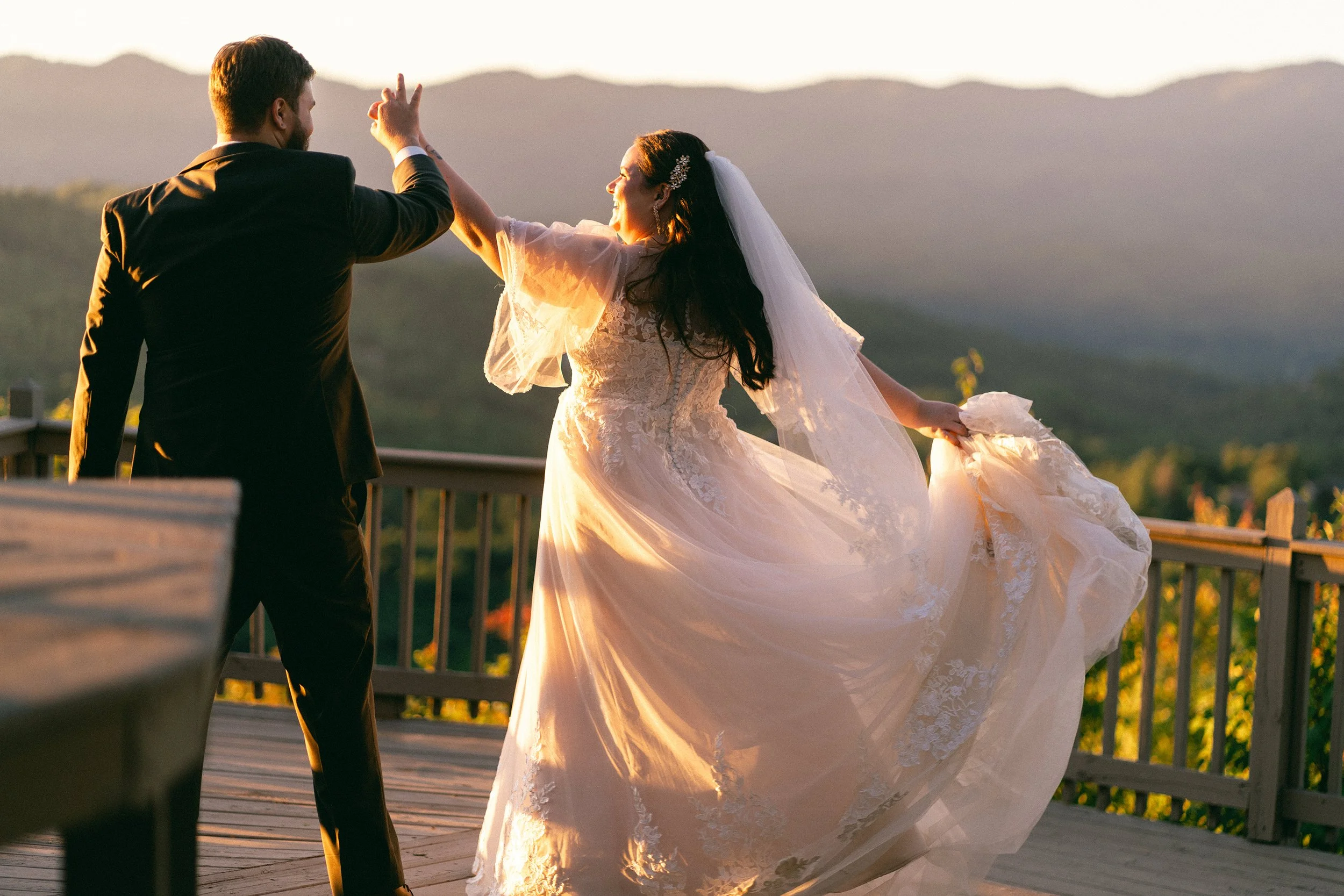 Couple celebrating on a mountain overlook deck during golden hour at their Appalachian elopement