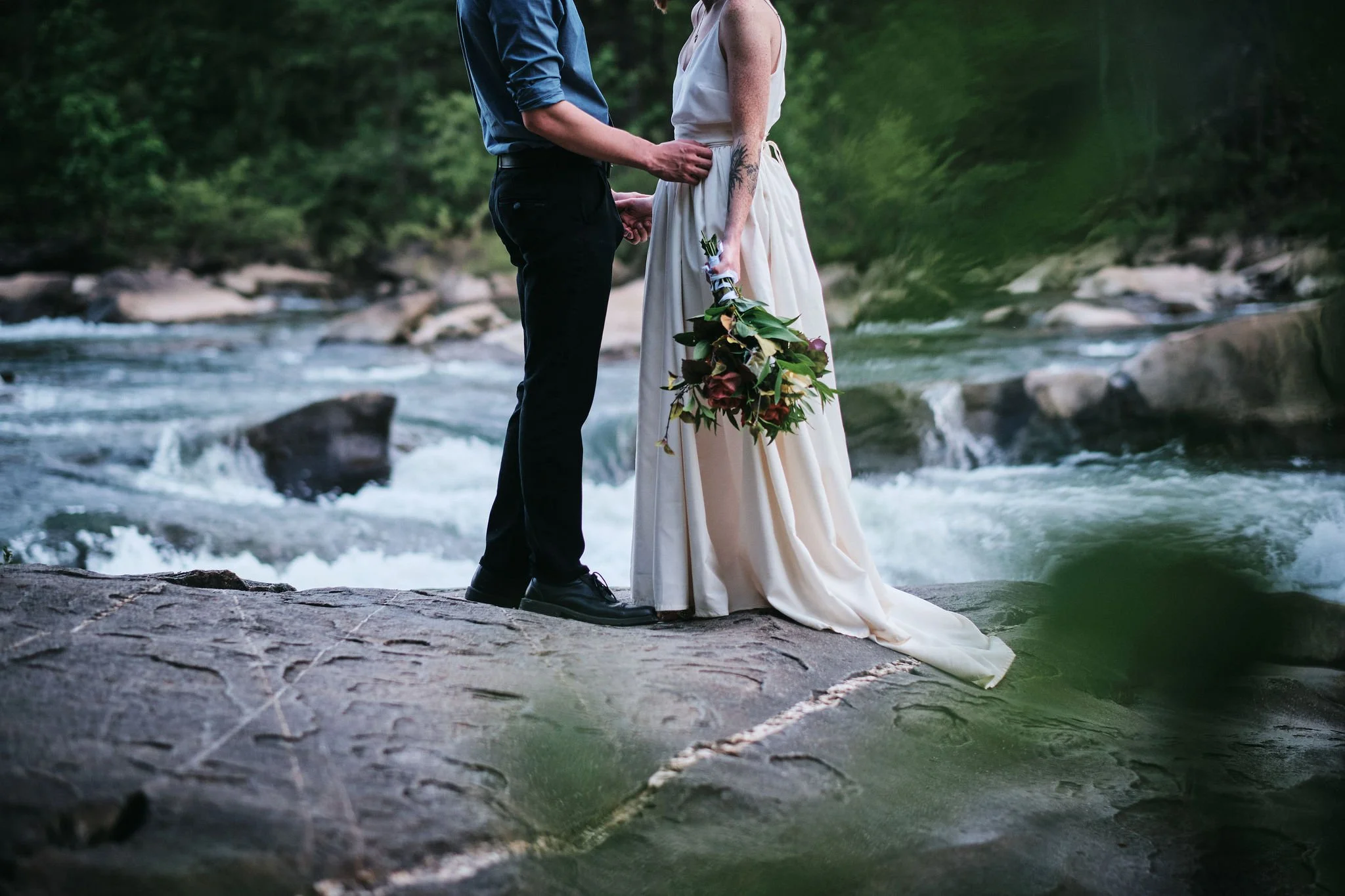 Margo wading into a North Georgia mountain river in her white elopement dress, fabric floating on the current, intimate Blue Ridge Georgia elopement photography by Appalachian Wedding Photography