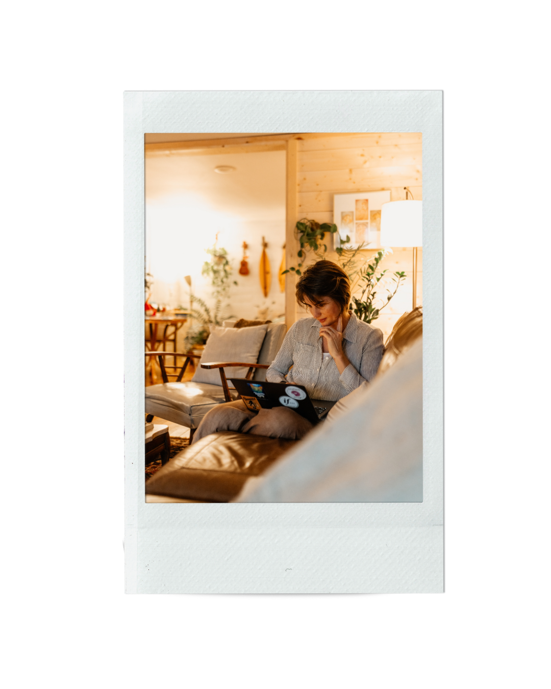 Emilie Gates Sitting on a Couch with a Laptop on her Lap Thinking.png