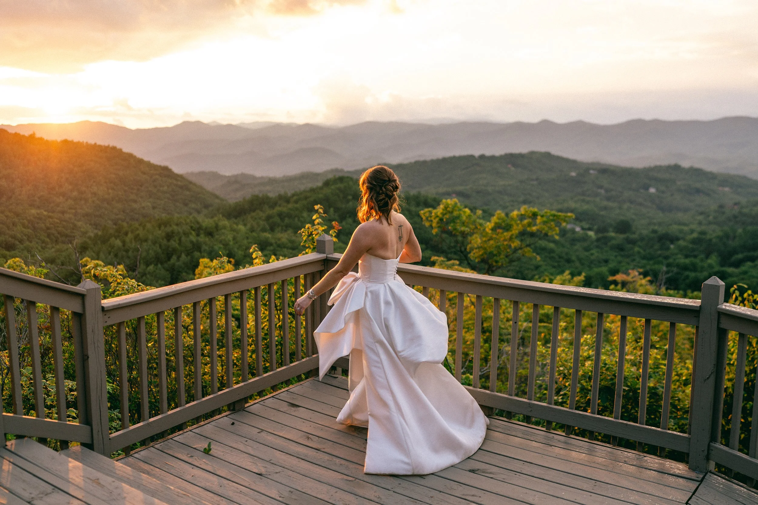Bride in a blush gown on a deck overlooking the Blue Ridge mountains during a golden sunset