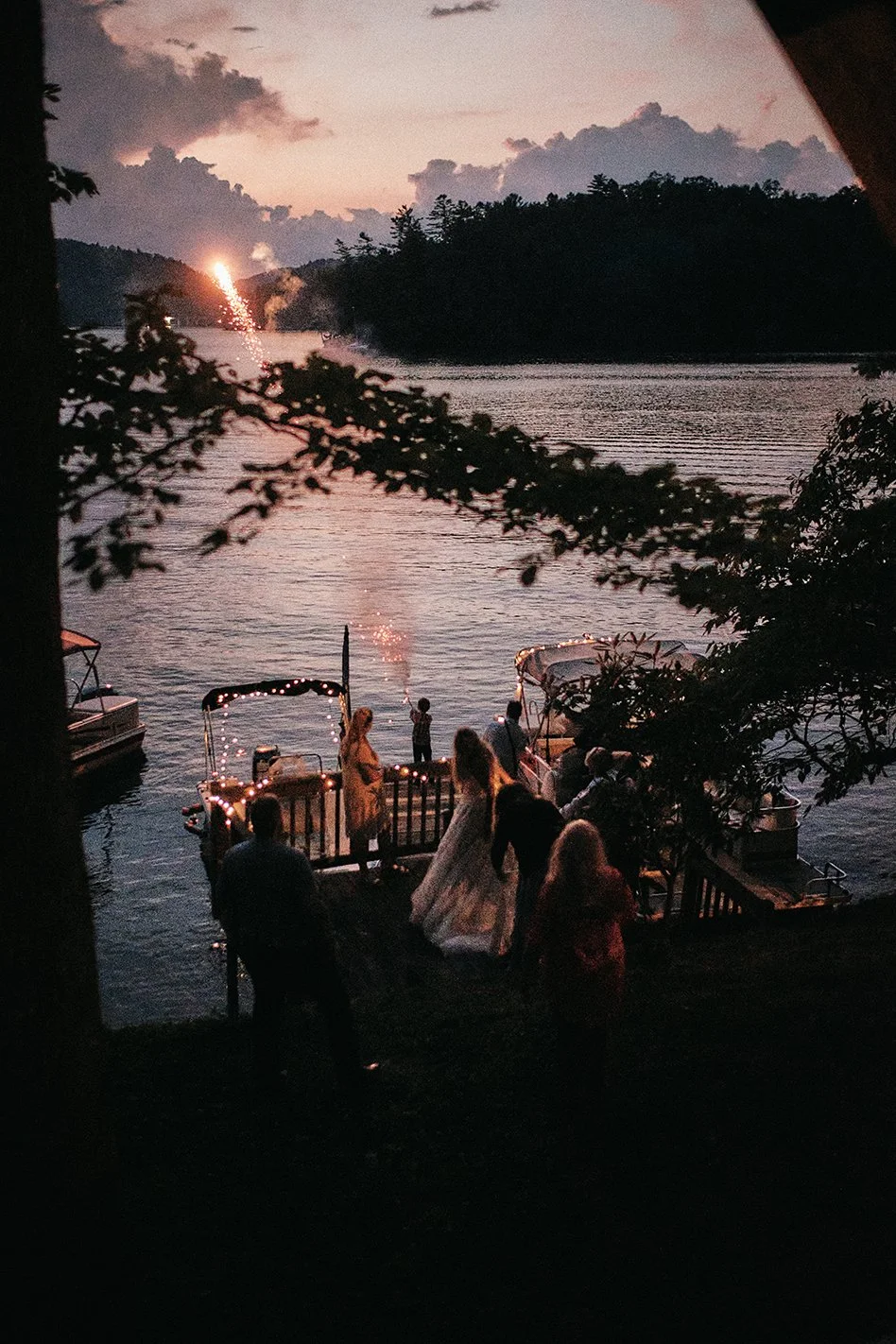 Fireworks over a lake with family gathered during an intimate Appalachian wedding celebration