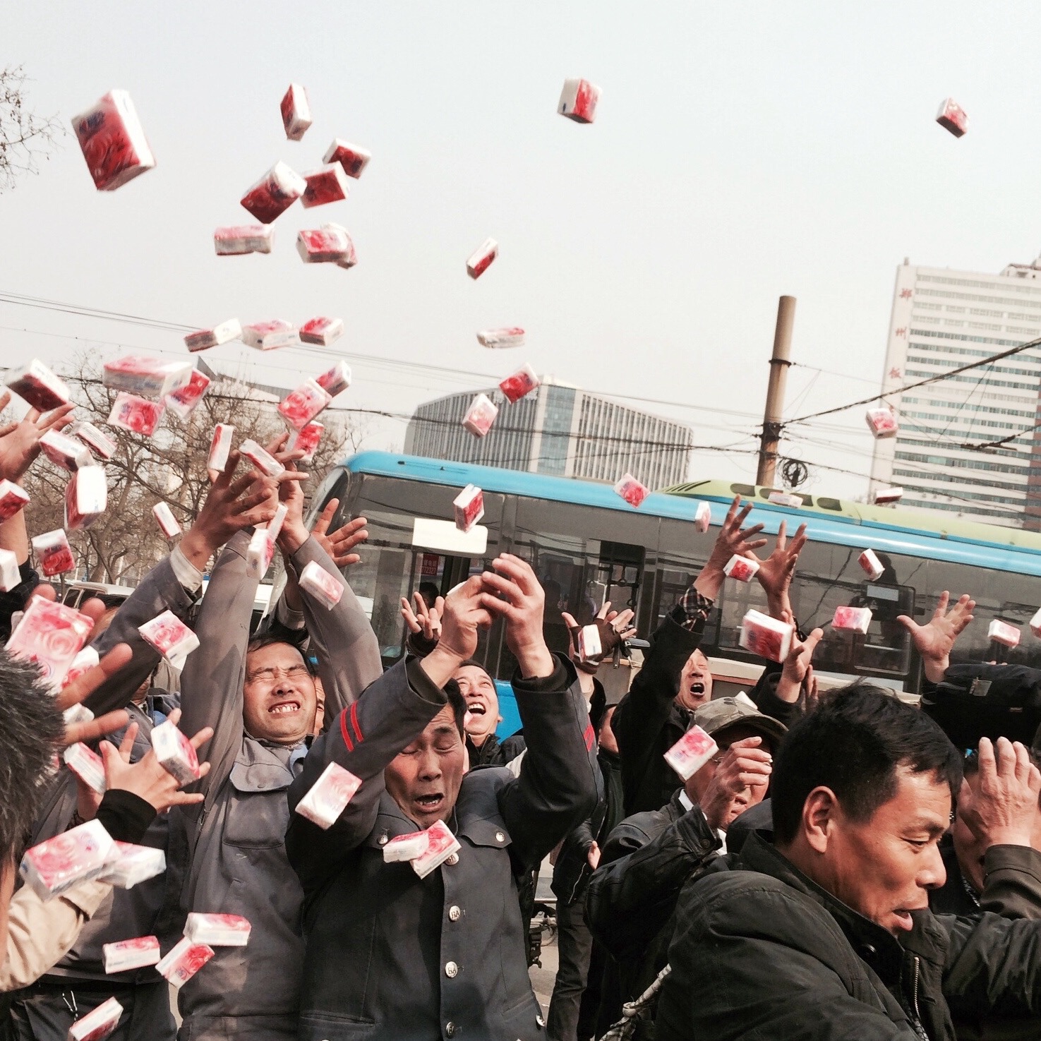 Factory workers scramble to catch free paper napkins thrown from a stage during a promotional event. Zhengzhou.