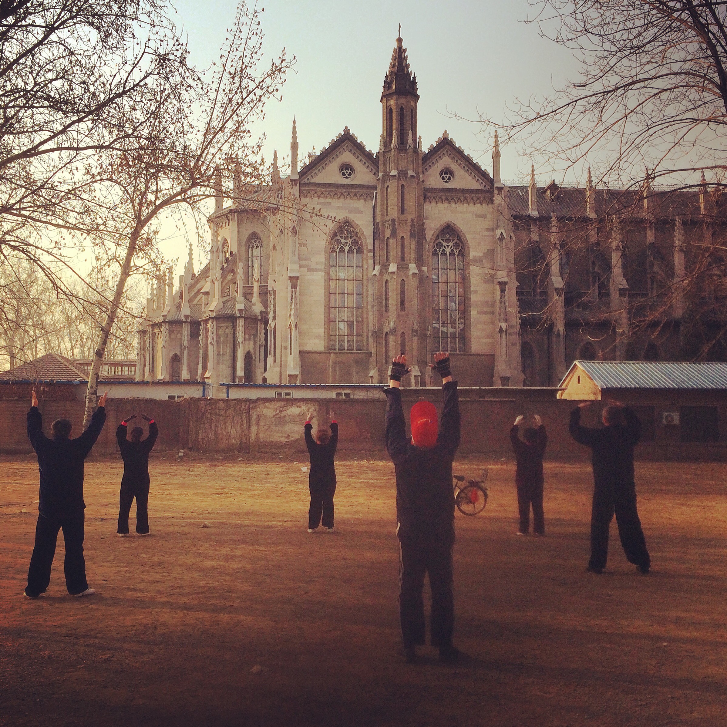 Elderly Chinese practice taiqi outside an old Catholic church, Jinan.