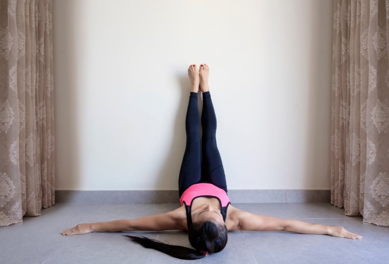 Woman doing yoga Legs Up or Viparita Karani variation yoga pose