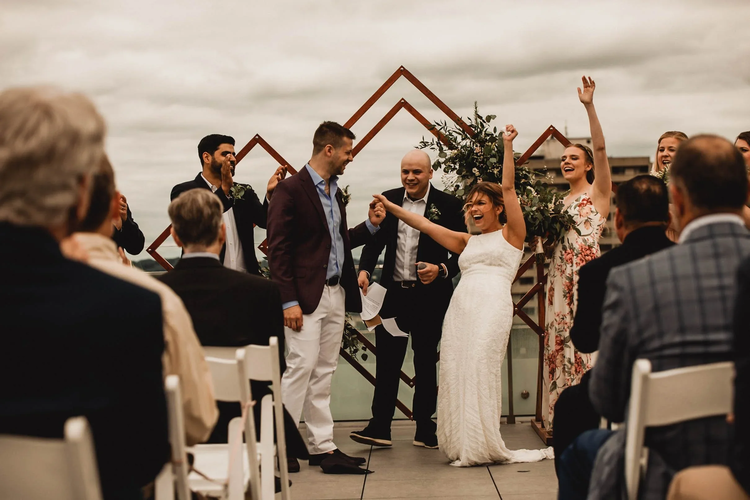 A couple throwing their hands in the air after their first kiss at their wedding ceremony