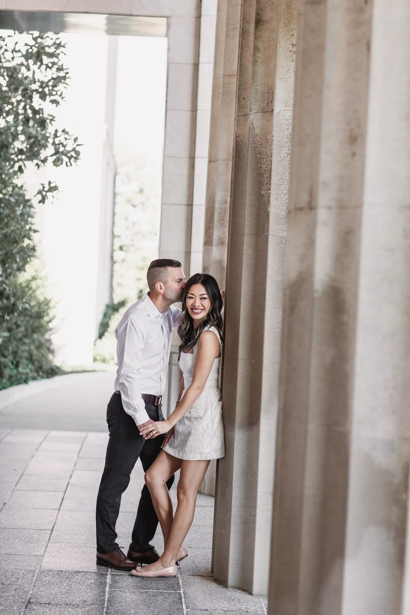 Kitty and Scott embracing beside tall stone columns outside the Cincinnati Art Museum.