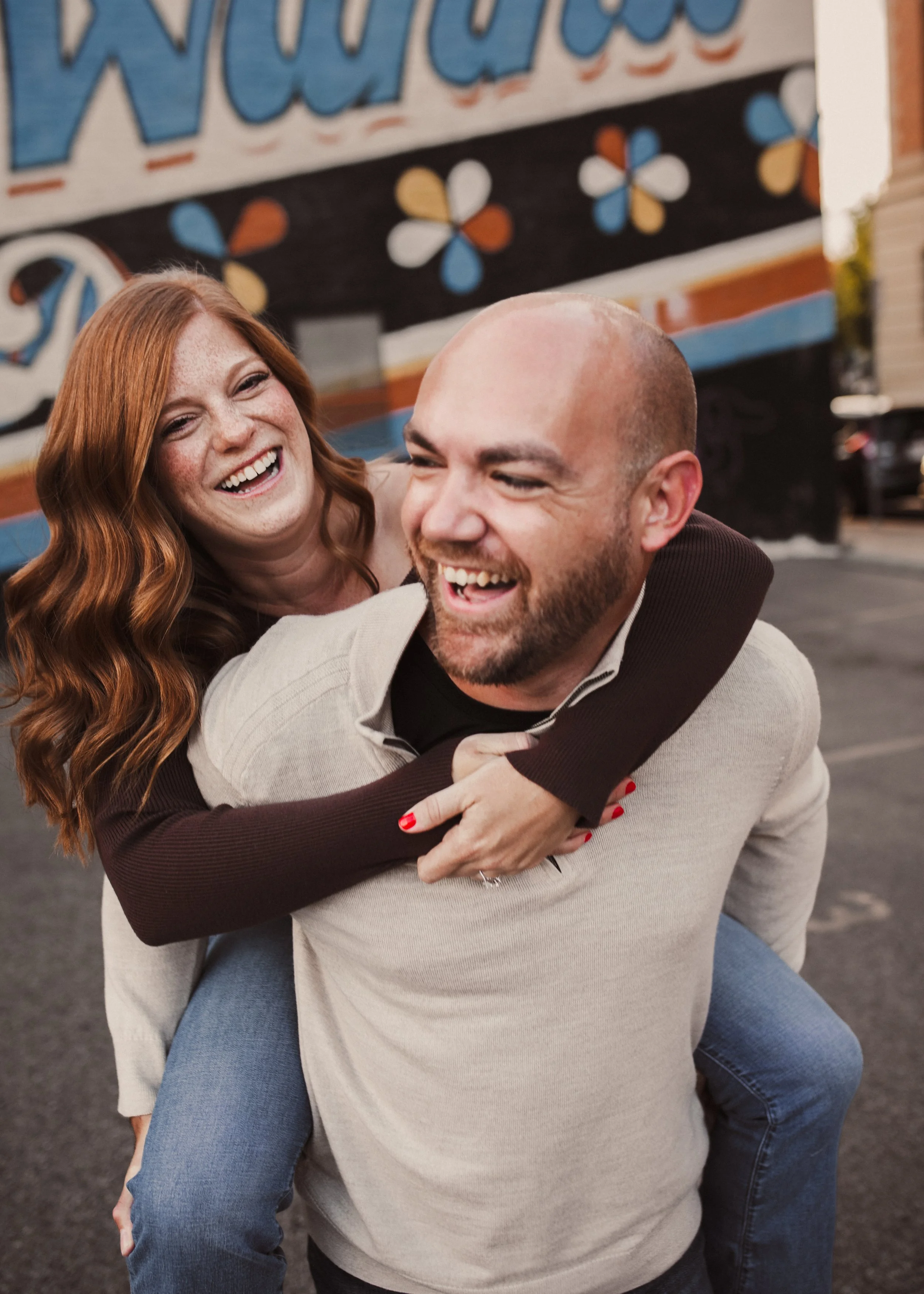 Couple laughing during a playful piggyback moment in their engagement session.