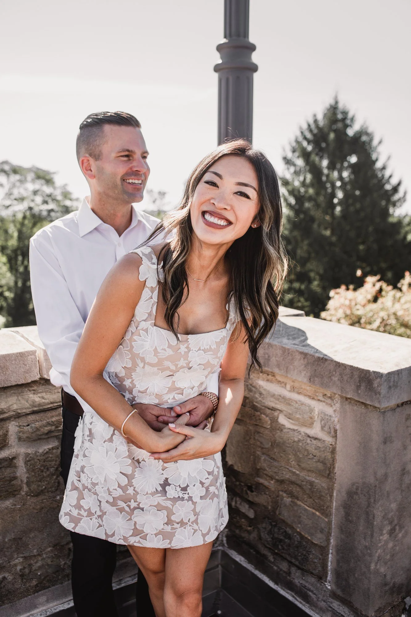 Kitty laughing as Scott holds her close beside a stone terrace railing.