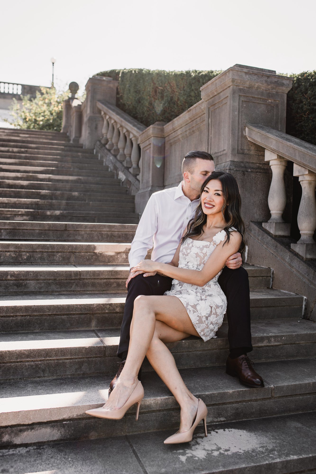 Kitty and Scott sitting close together on wide stone steps beside a balustrade.