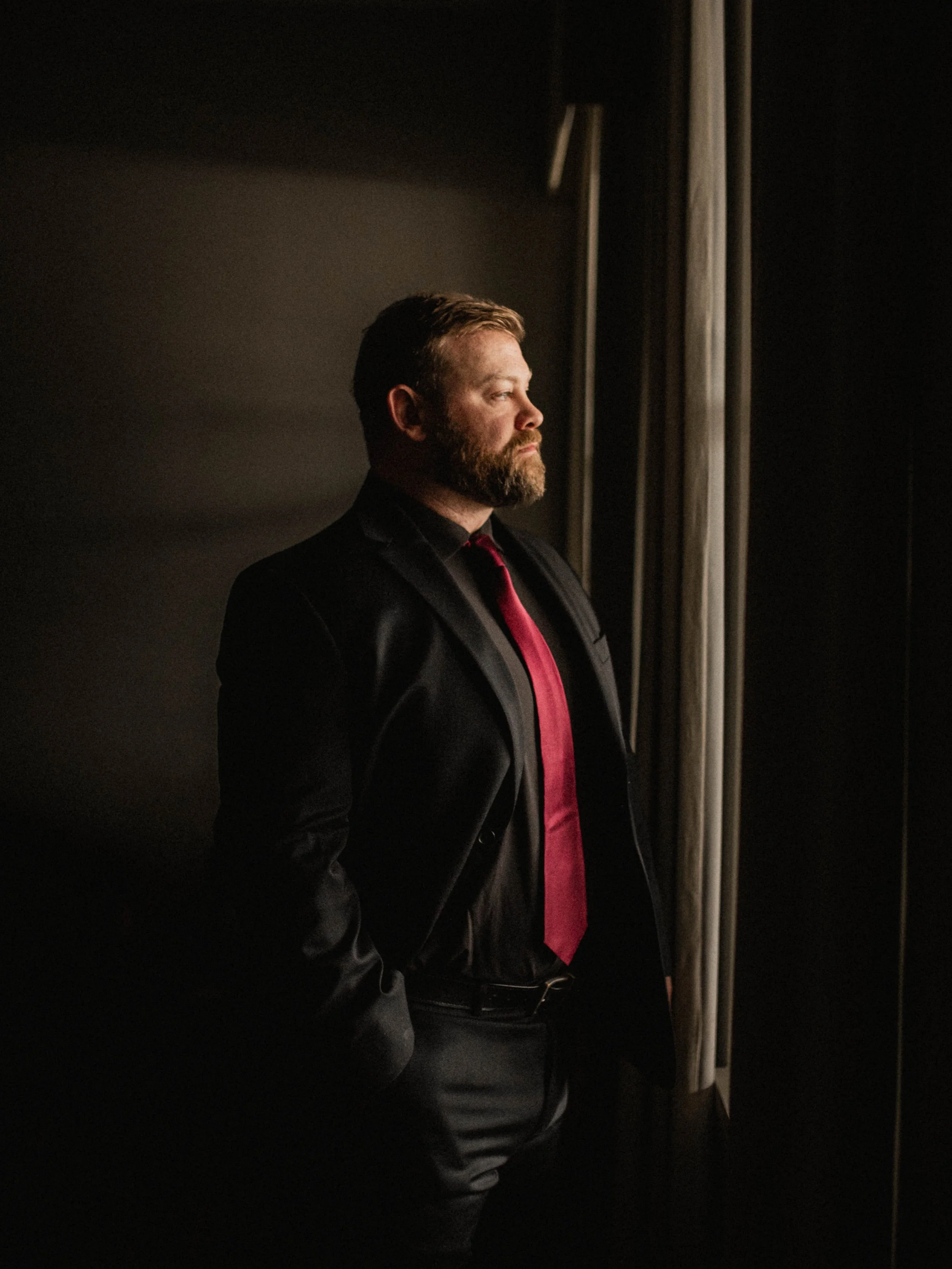 Groom Tony standing by a window during his wedding at The Landing Event Center in Loveland, Ohio.