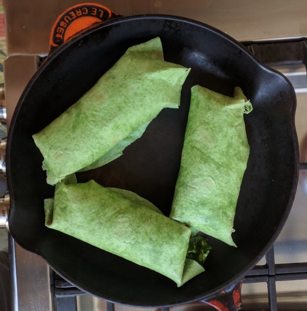 Placing the wraps into a skillet (or a sandwich press) seam side down to toast the tortilla and wilt the inner ingredients.