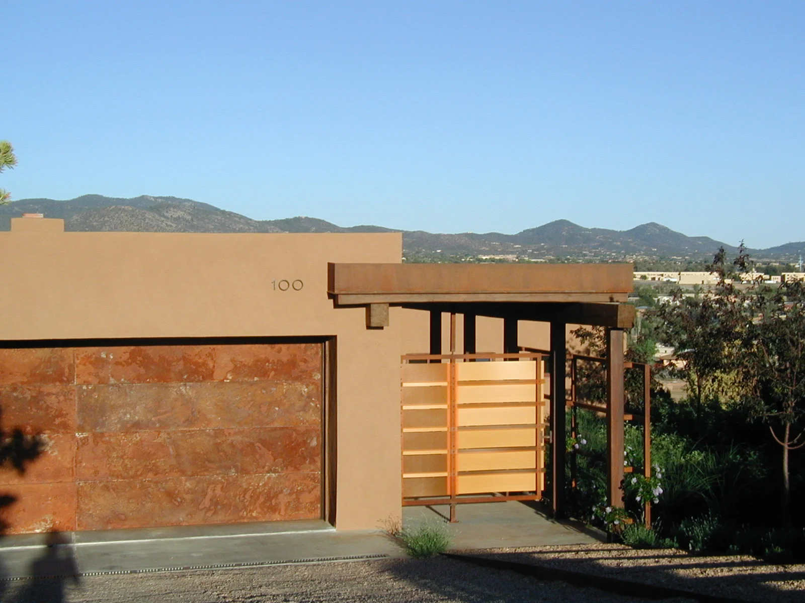  Lanier Residence  The steeply sloping cul-de-sac lot necessitated having the garage door on the front of the home, but the yellow/orange pivot gate, custom designed with the client, draws the eye to the pedestrian entrance. 