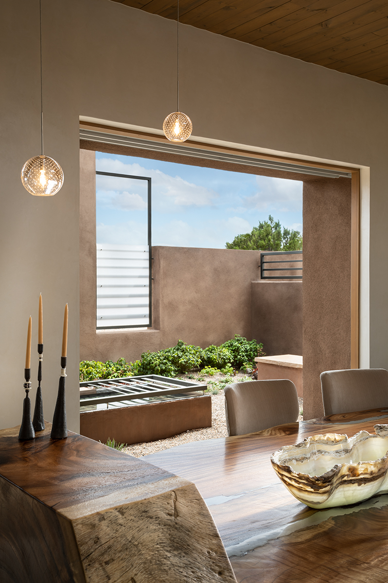 Three large pocketing doors on different walls of this Great Room give the occupants the feeling of being outside but protected from the elements. This particular door opens to a small ‘Oasis’ with a water feature and steel screens which offer privacy from the driveway and road.