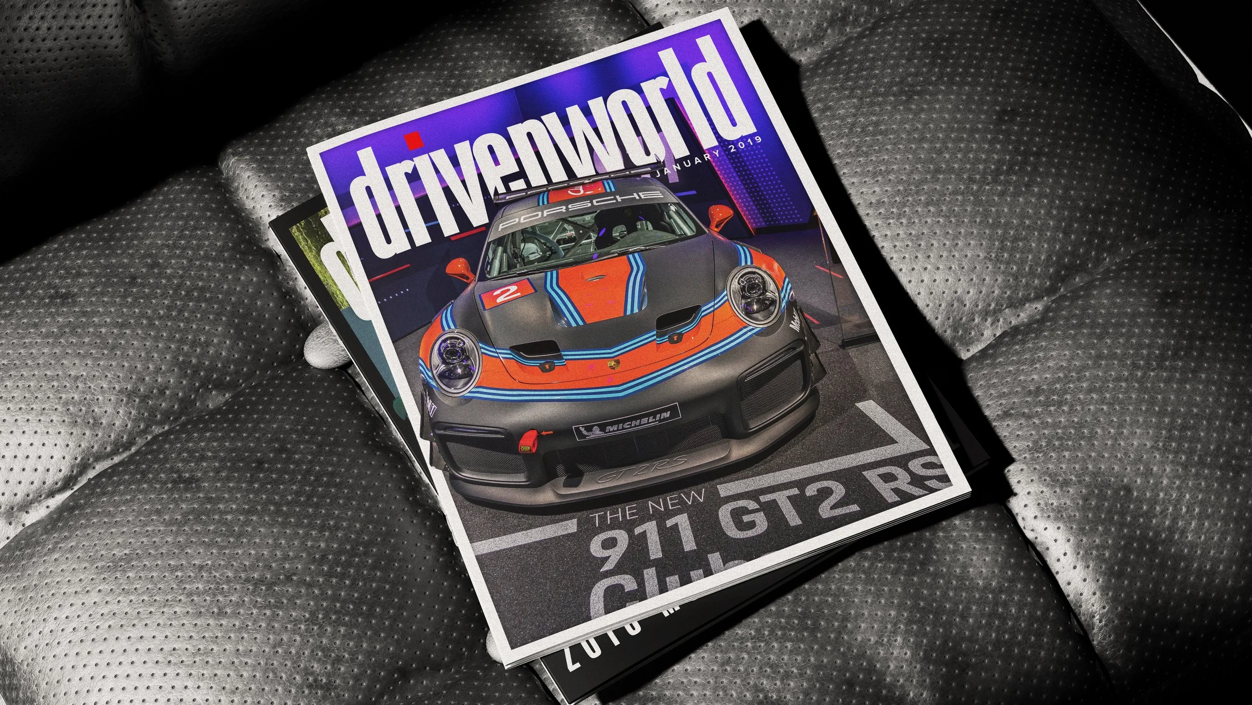 A car magazine featuring a Porsche 911 GT2 RS sports car on its cover, laid on a textured surface.