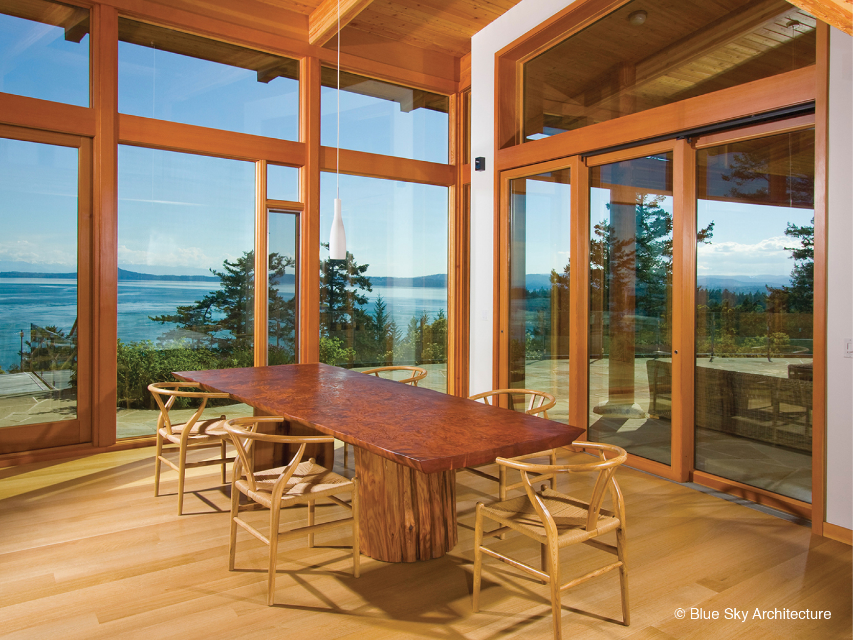 Wood slab table in dining room with floor to ceiling wood windows