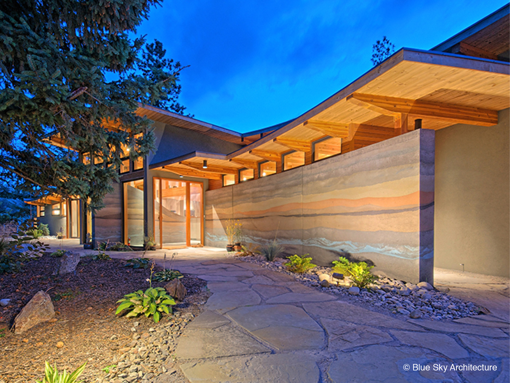 Rammed earth and heavy timber entryway on custom home design 