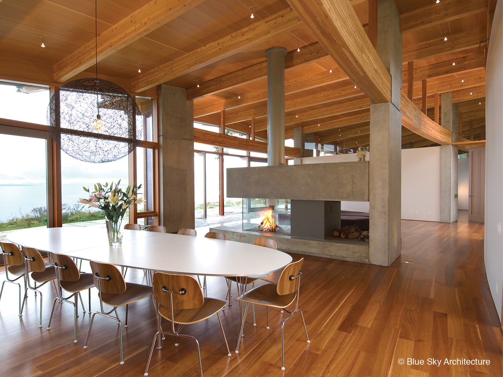 Dining room with concrete fireplace and wood rafters