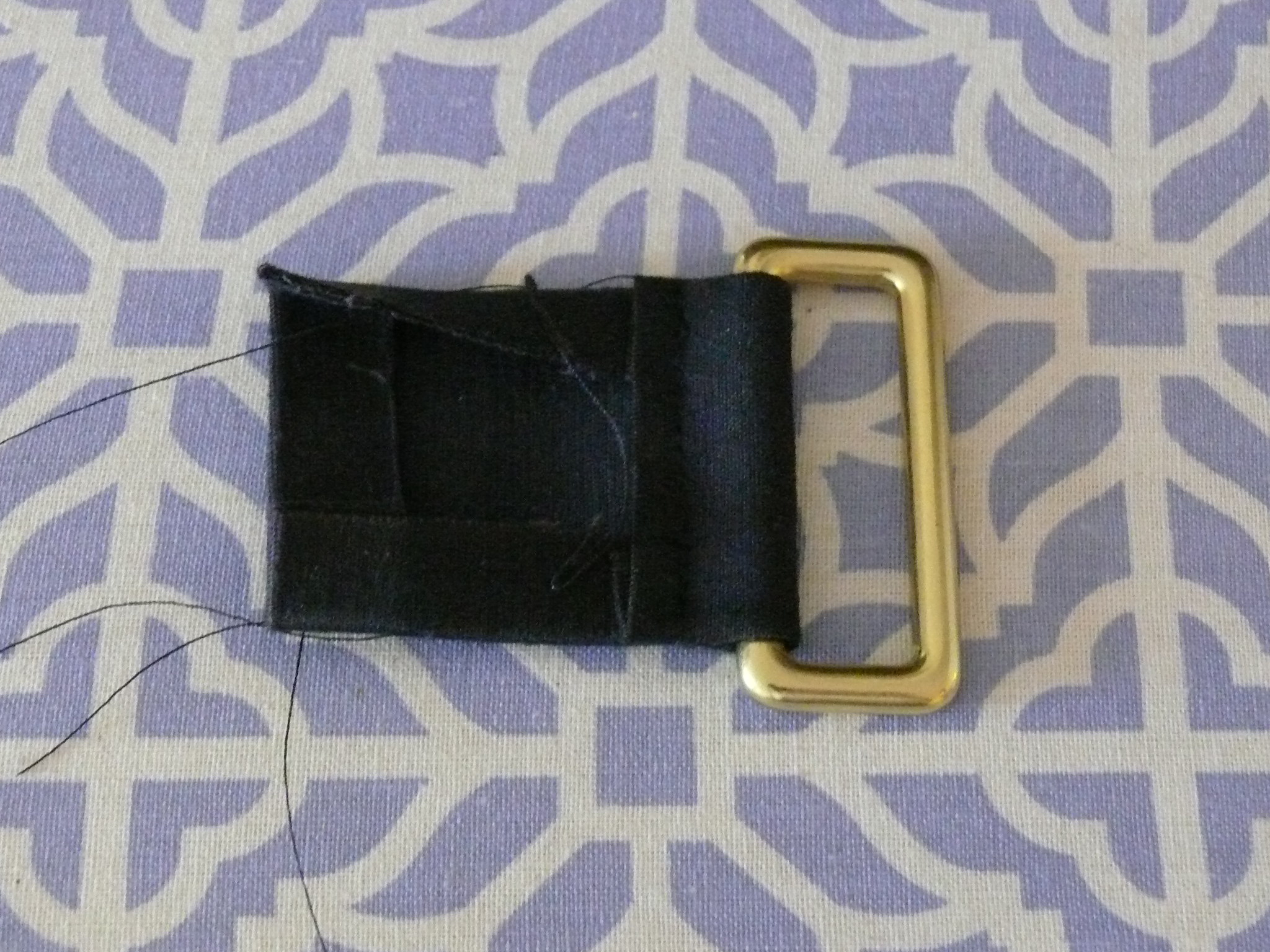 Using a 6.5 cm x 8.5 cm piece of fabric, fold over 1 cm seams on sides and bottom, and a 3 cm seam on the top that loops through the brass ring...