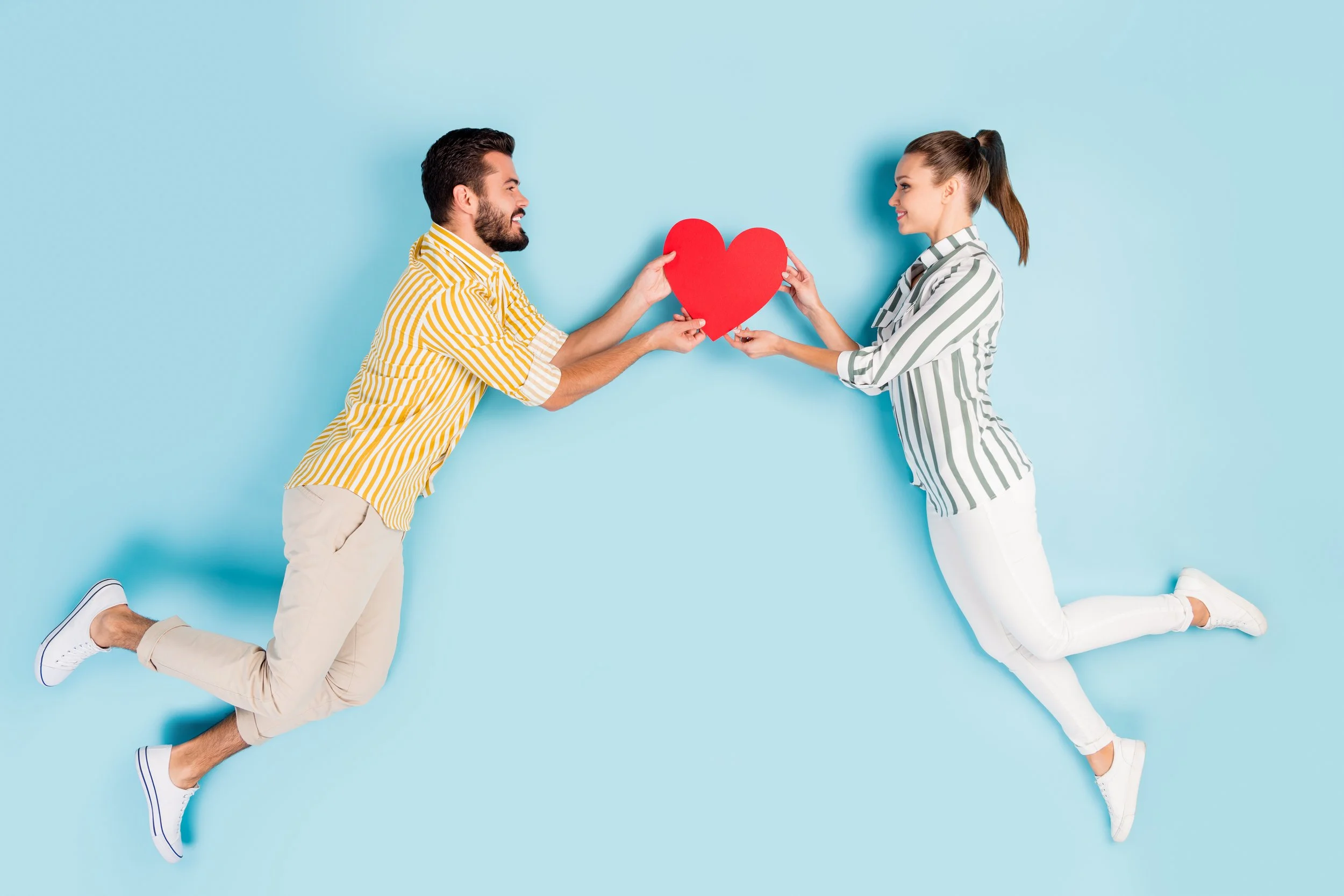 Couple joyfully holding a paper heart between them