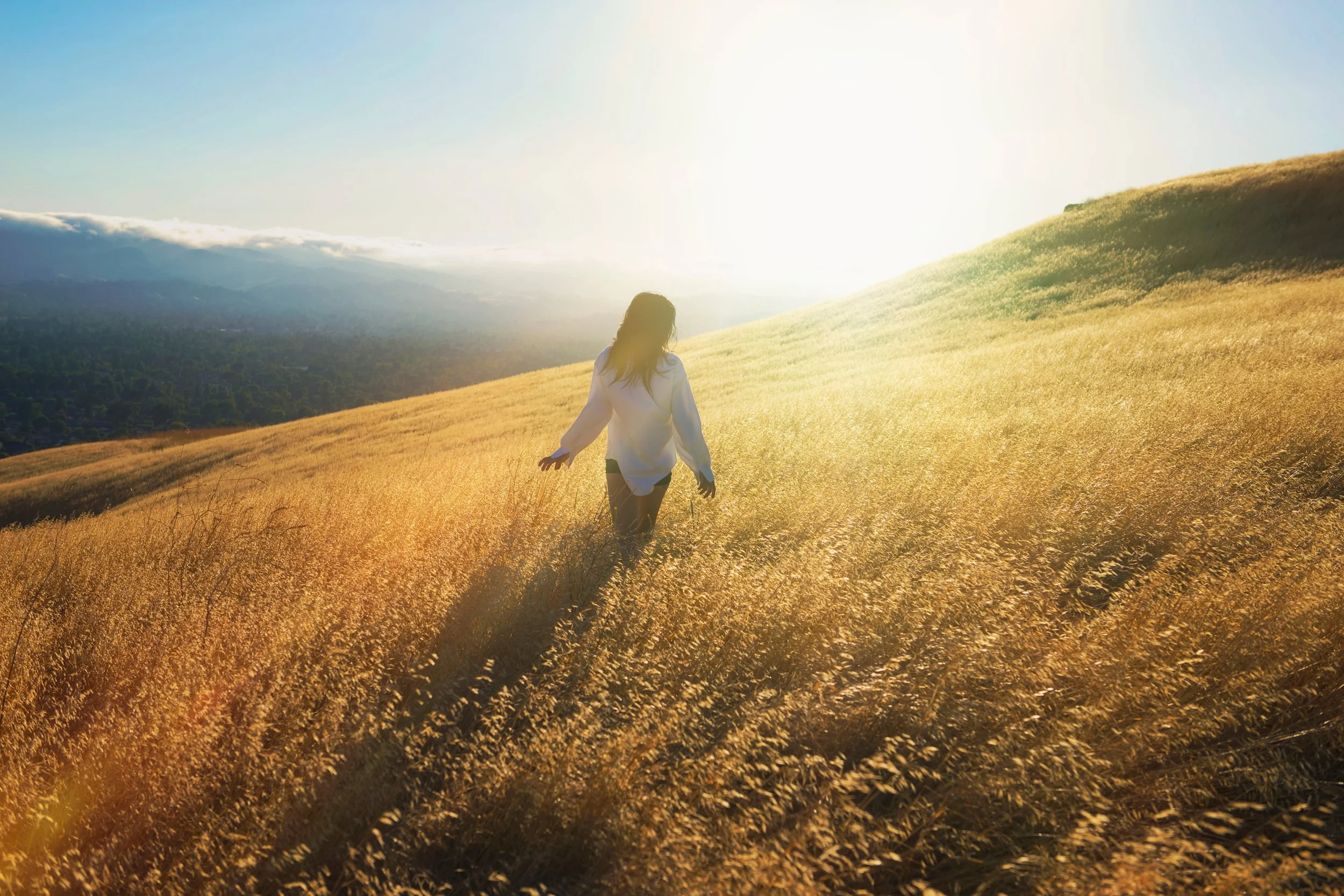 Woman walking peacefully through a sunlit golden field