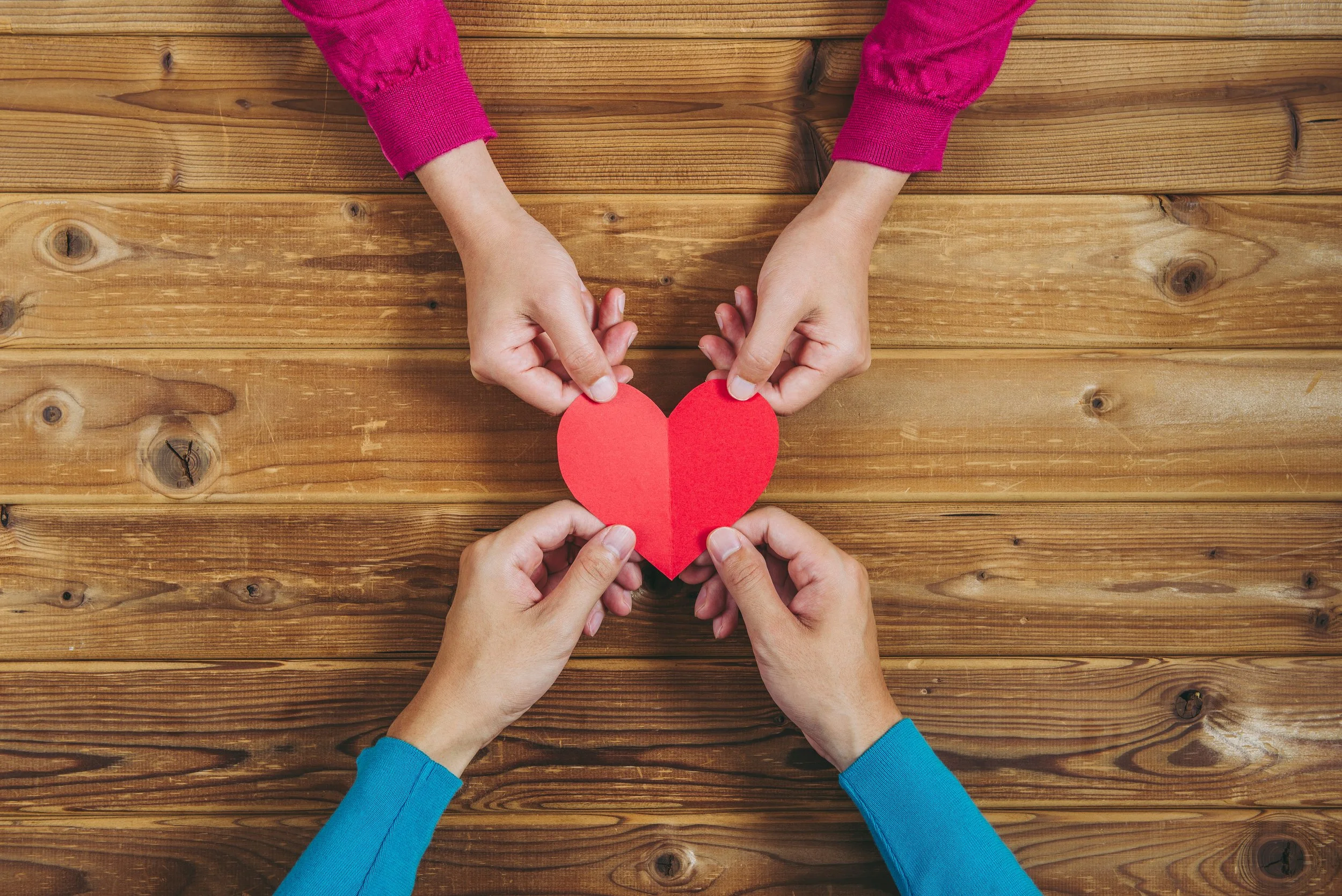 A couple holds a paper heart