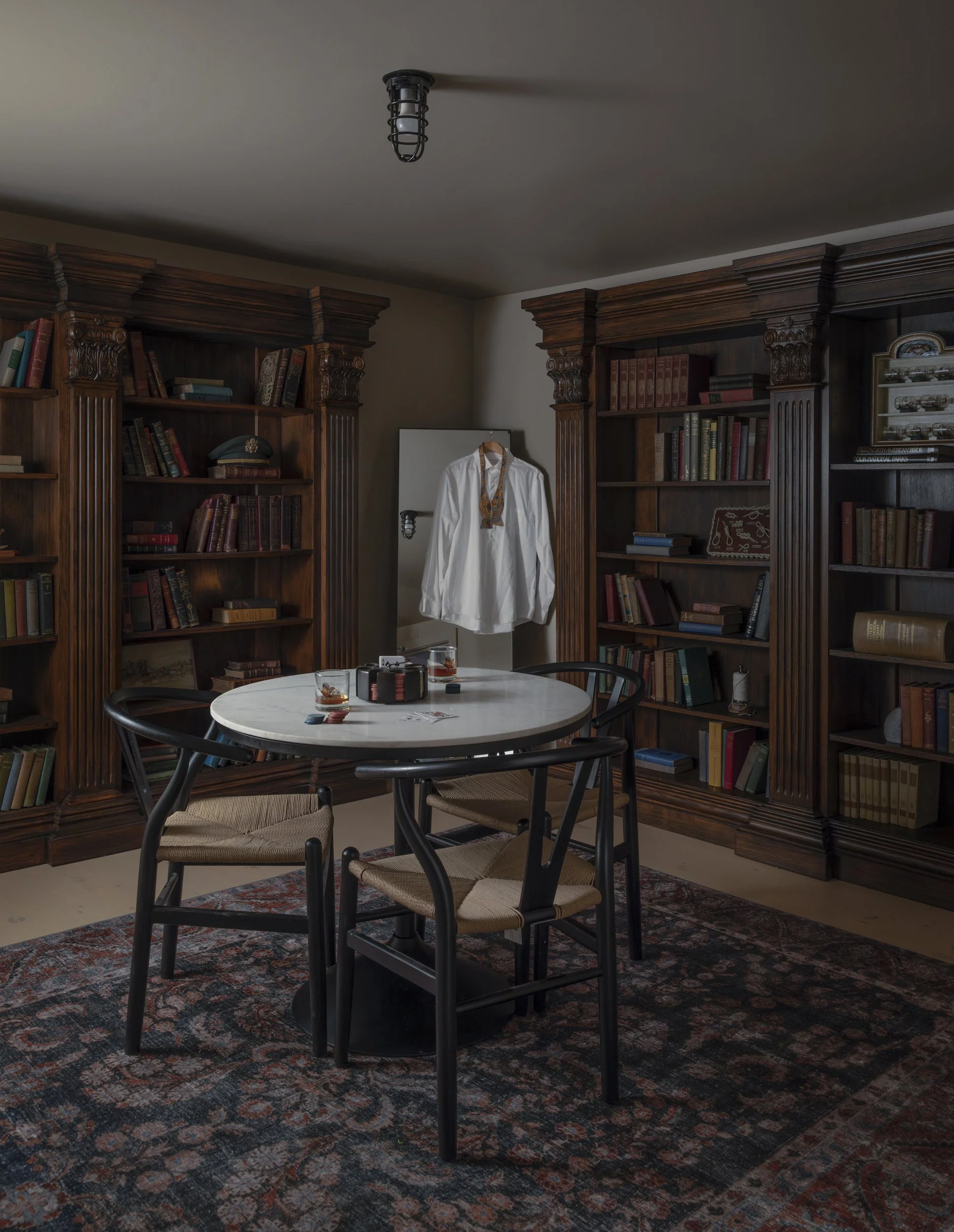 Library with dark wood bookcases, round marble table and patterned rug at the Patterson