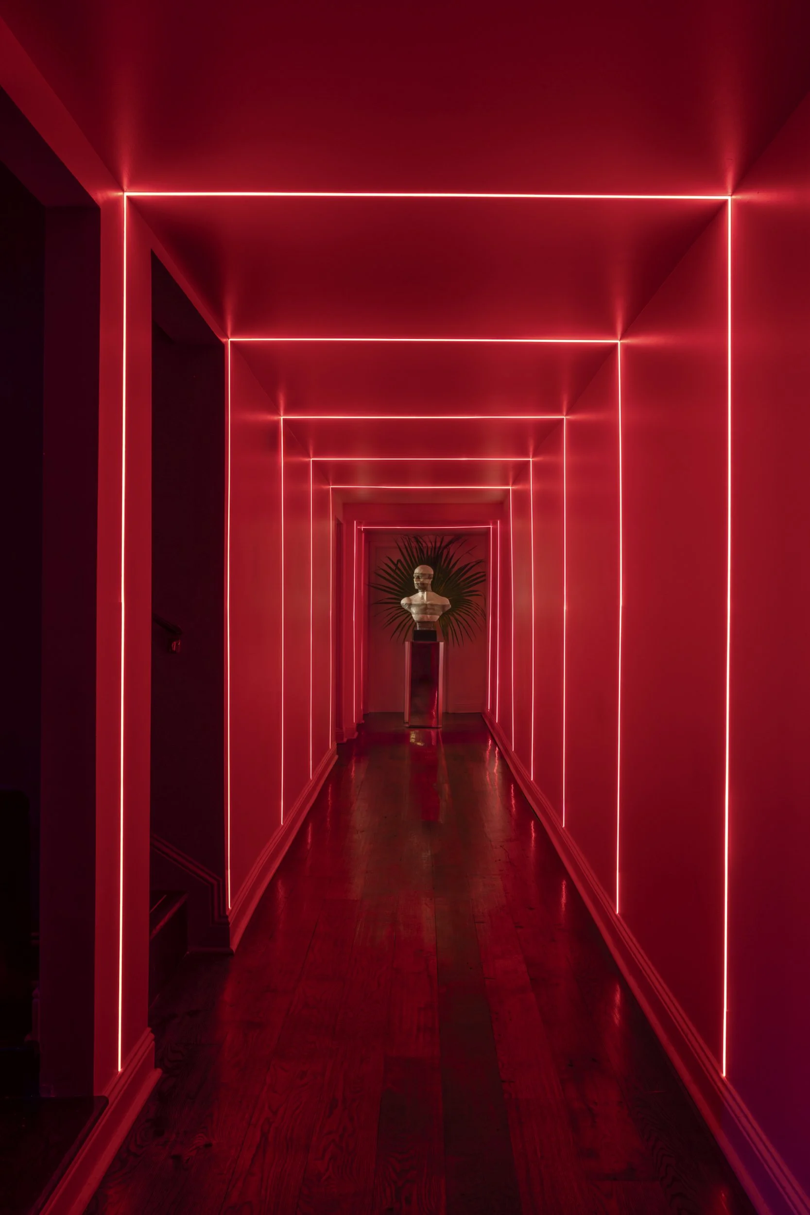 Neon-lit red corridor leading to a marble bust at Mother’s, Baton Rouge